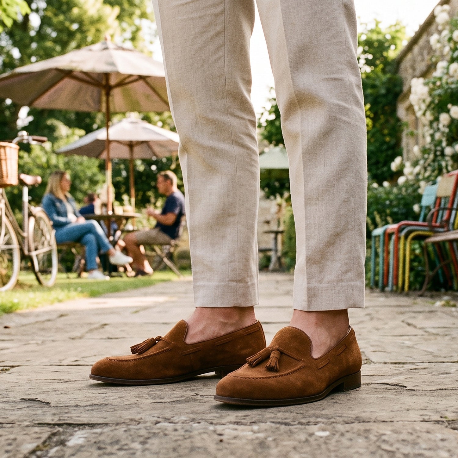 Men's loafers with light beige linen trousers and classic brown suede tassel loafers.