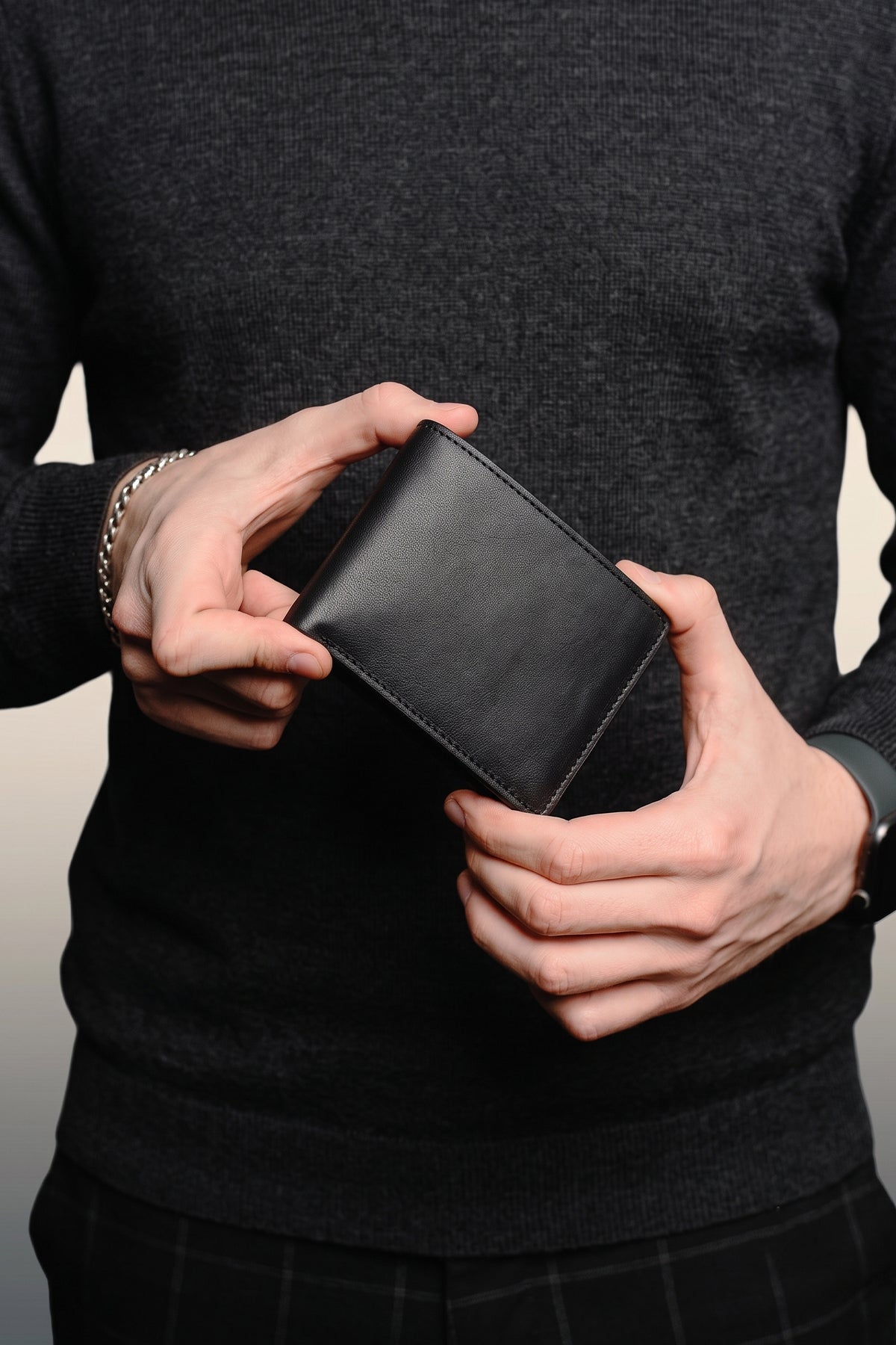Man holding Oxford black luxury leather bi-fold wallet for men by Oswin Hyde – premium smooth leather wallet with silver embossed logo and multiple card slots.