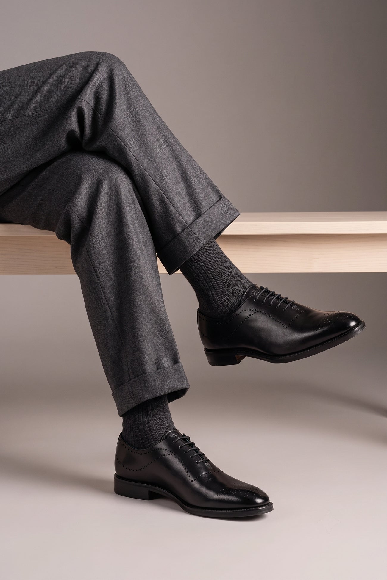 Model wearing Men’s Melton Oxford shoes in black leather with classic closed lacing and elegant detailing, perfect for formal and refined dress codes.