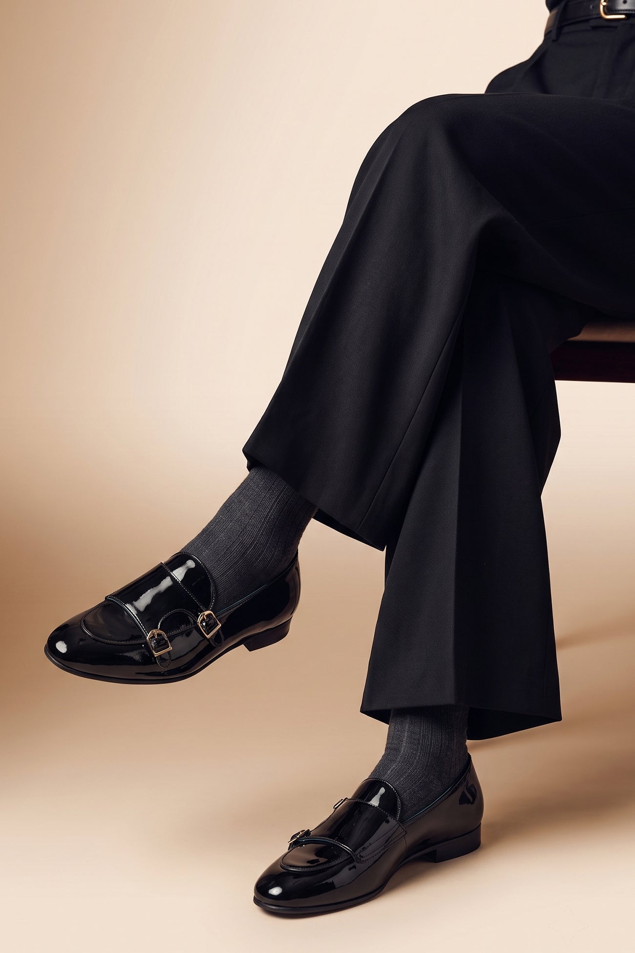 Model wearing Clifford Black patent monk leather loafers for men featuring glossy patent leather and classic monk strap design for elegant formal occasions.