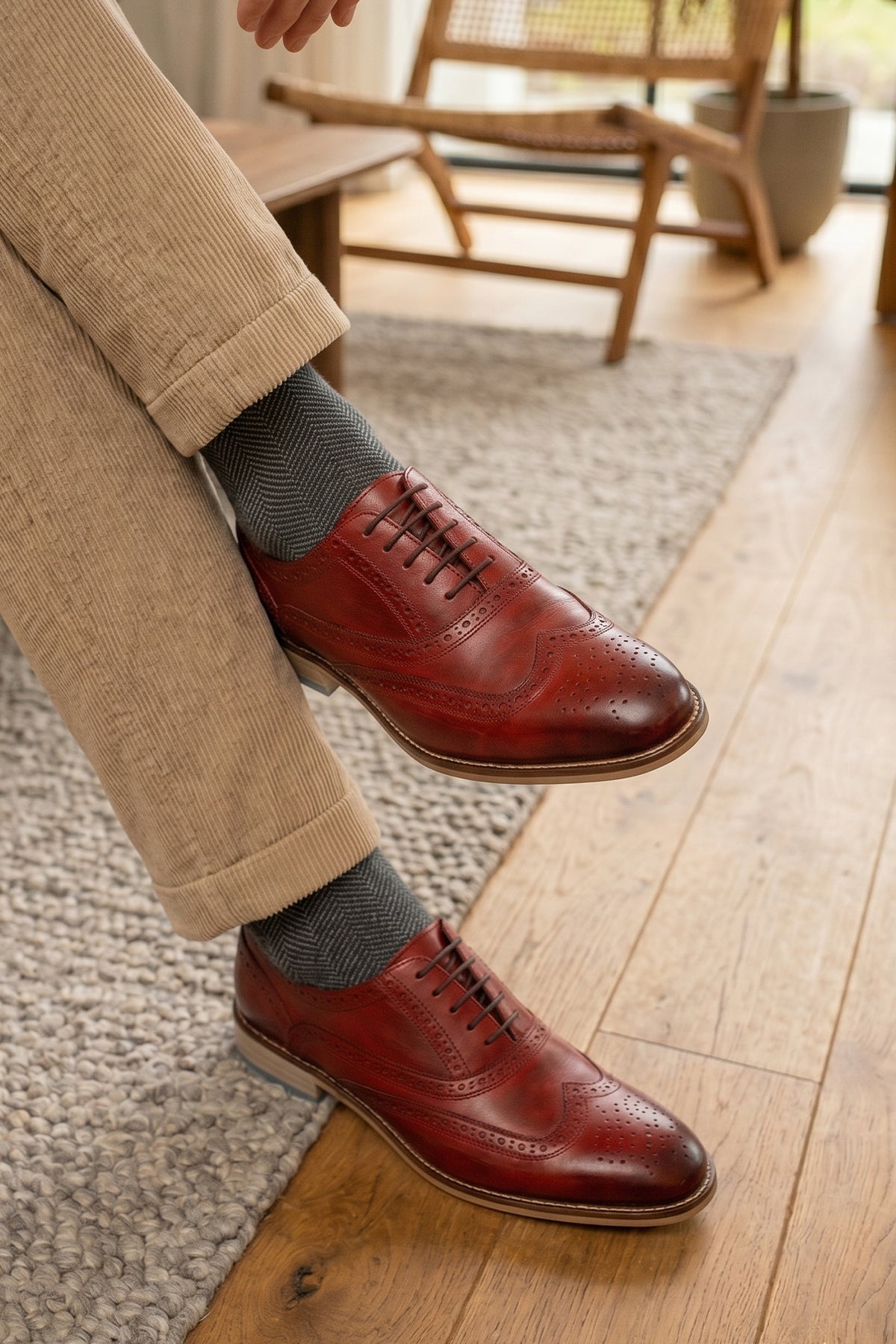 Man waringWinston cherry leather Oxford brogues for men featuring wingtip perforations and polished finish, ideal for formal and smart-casual occasions.