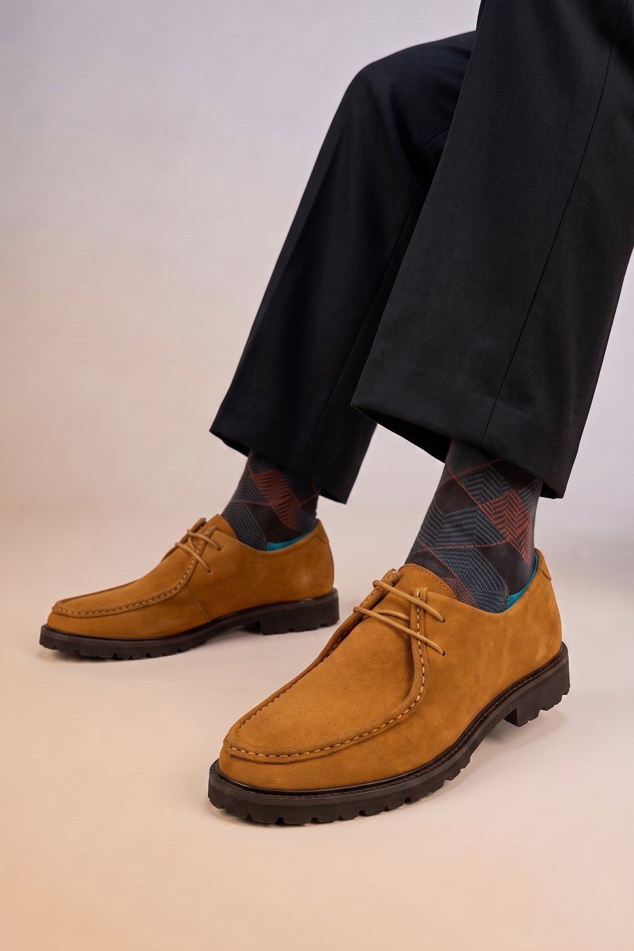 Model wearing Men’s Joshua tobacco suede Wallabee shoes with moccasin stitching, natural crepe sole and relaxed smart-casual design.