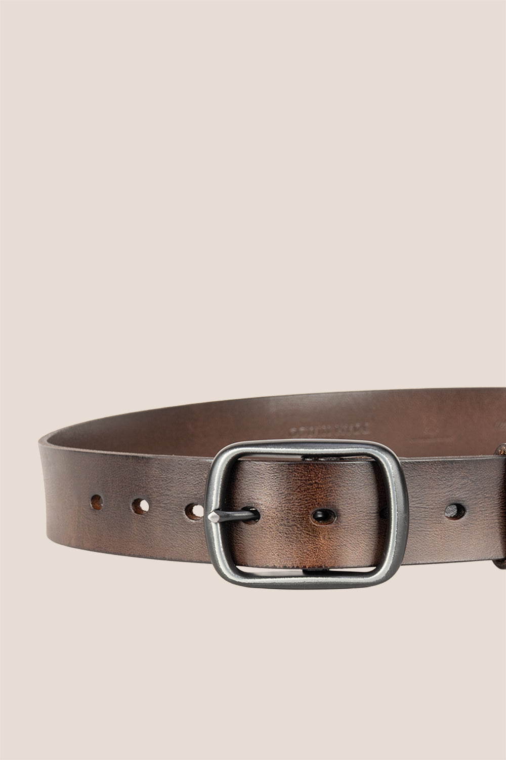 Brown leather belt with a silver buckle on a beige background