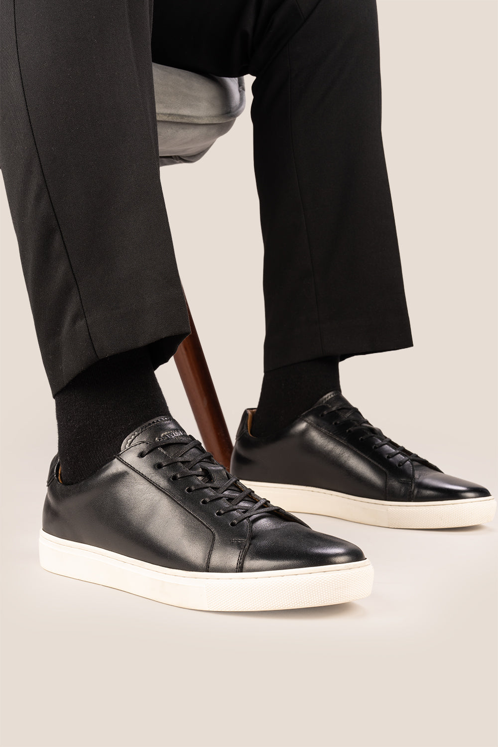 Black leather sneaker on a beige background