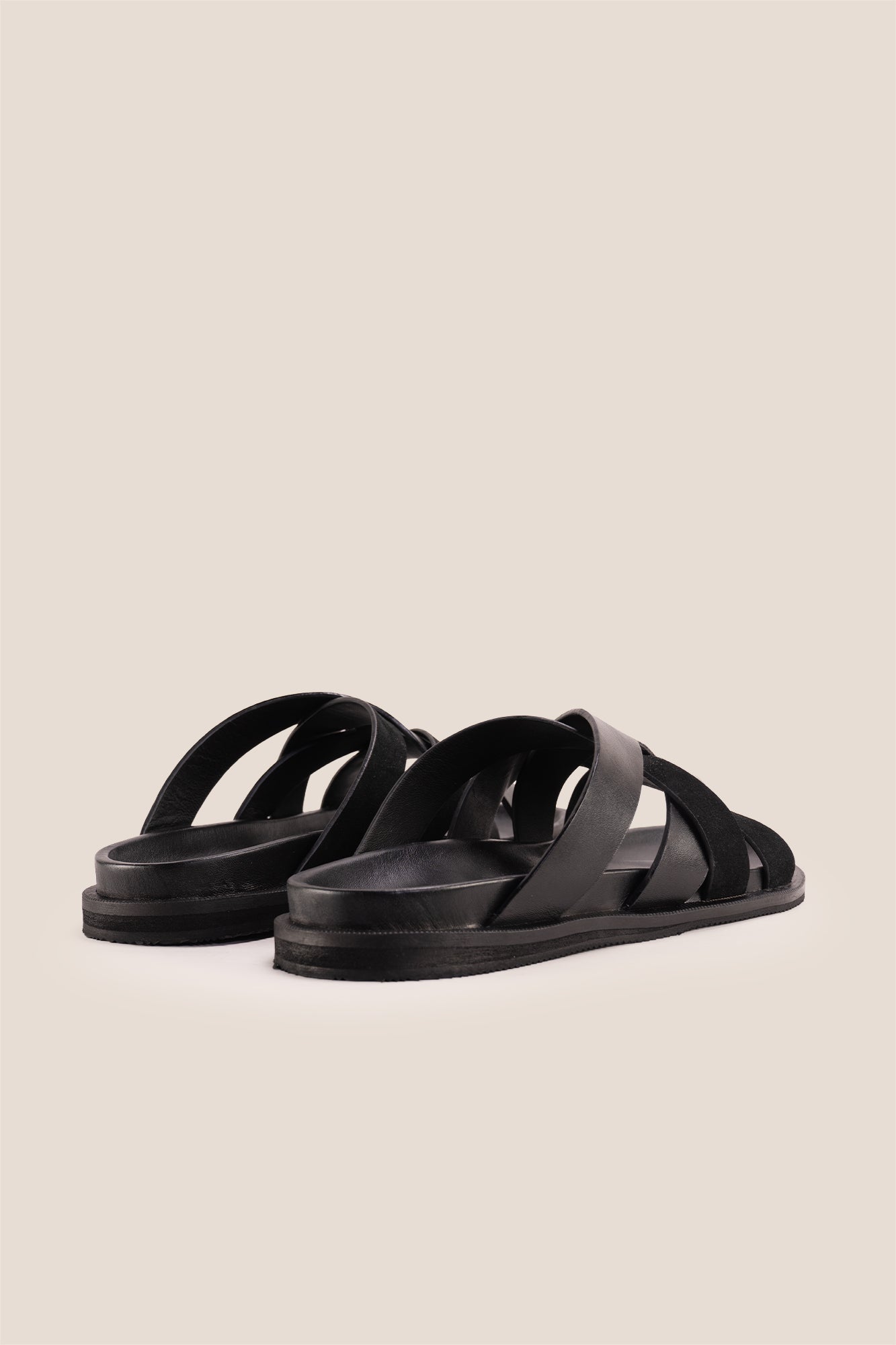 Men’s Rowan Black slide sandals featuring a minimalist black leather X-strap design and a sleek matte finish.