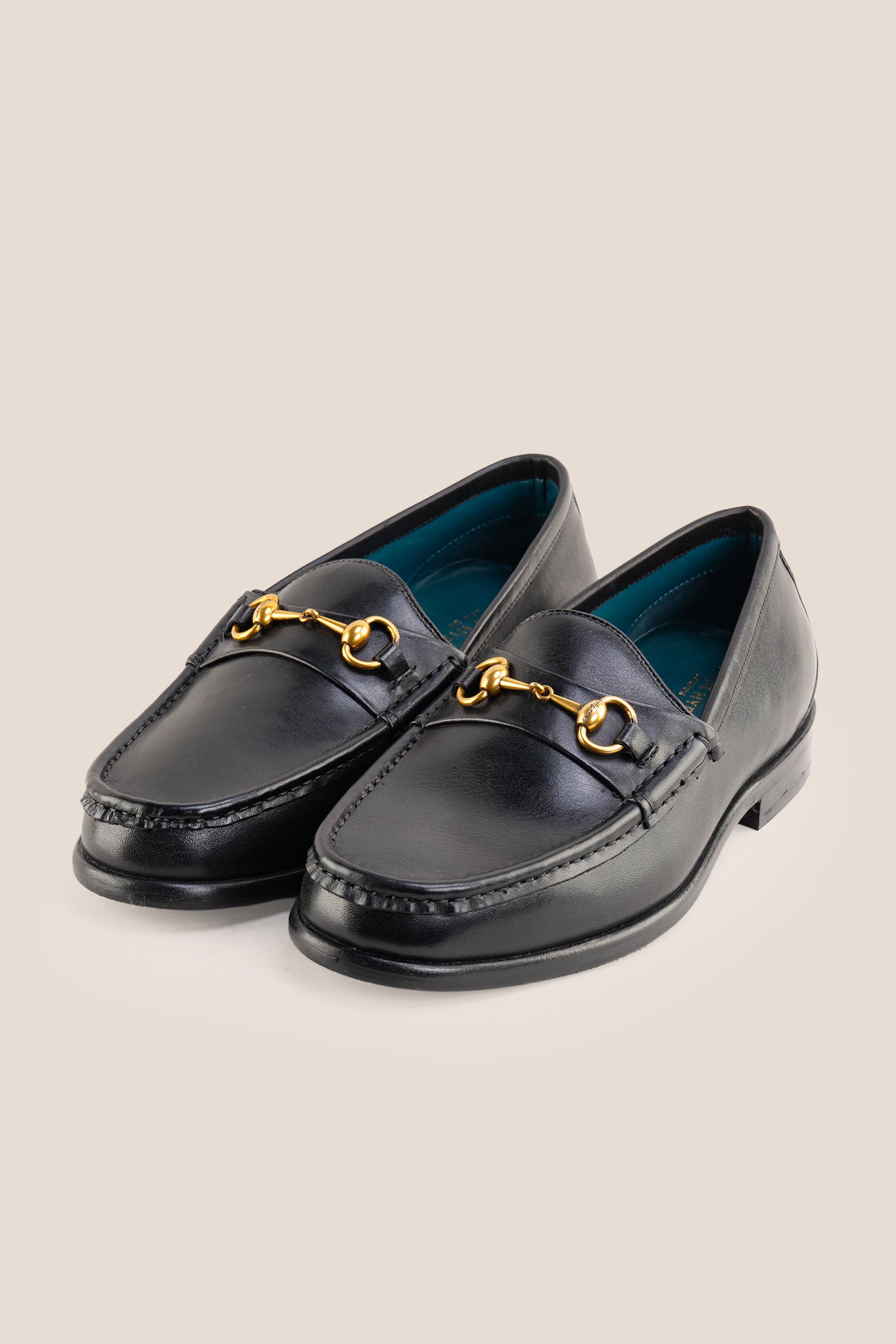 Pair of Oswin Hyde Samuel black leather horsebit loafers with gold buckle detail and teal lining.