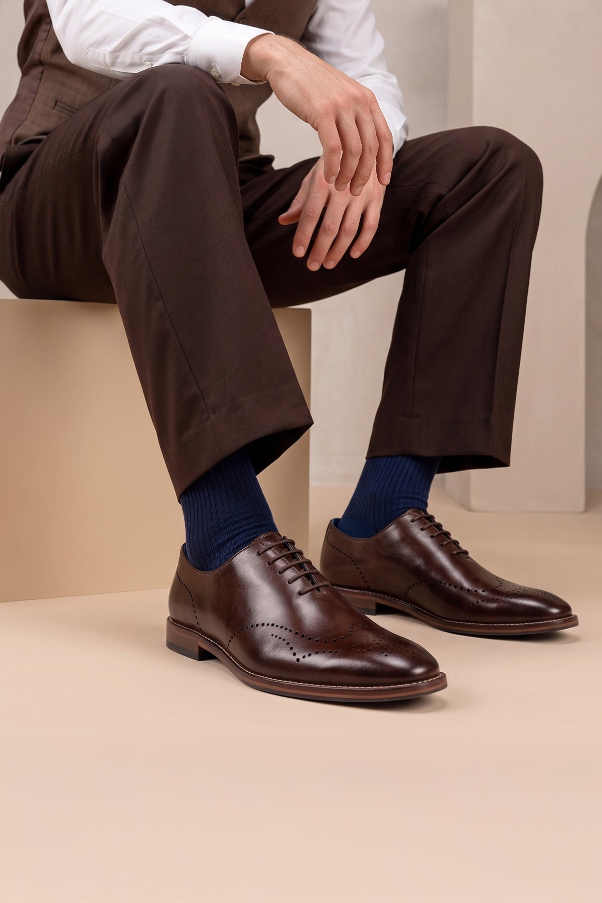 Man wearing Oswin Hyde London premium Oakley brown leather wingtip brogues with a toe medallion pattern, contrast welt stitching, and a cushioned teal interior.