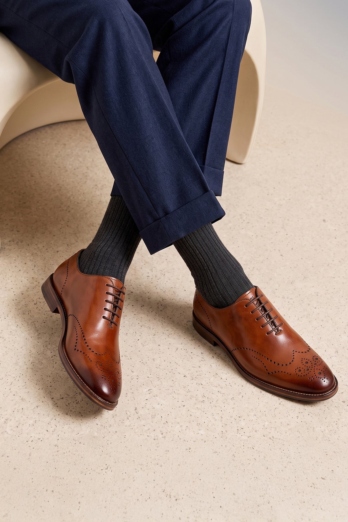 Man wearing Oswin Hyde London premium Tan leather wingtip brogues with a toe medallion pattern, contrast welt stitching, and a cushioned teal interior.