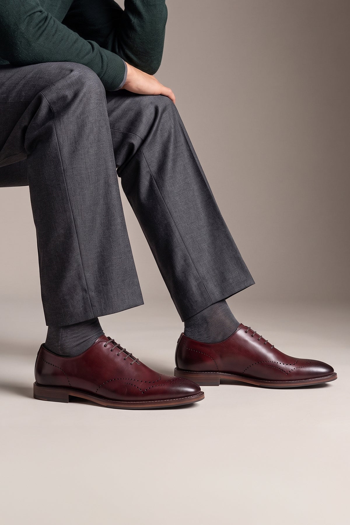 Man wearing Oswin Hyde London premium bordo leather wingtip brogues with a toe medallion pattern, contrast welt stitching, and a cushioned teal interior.