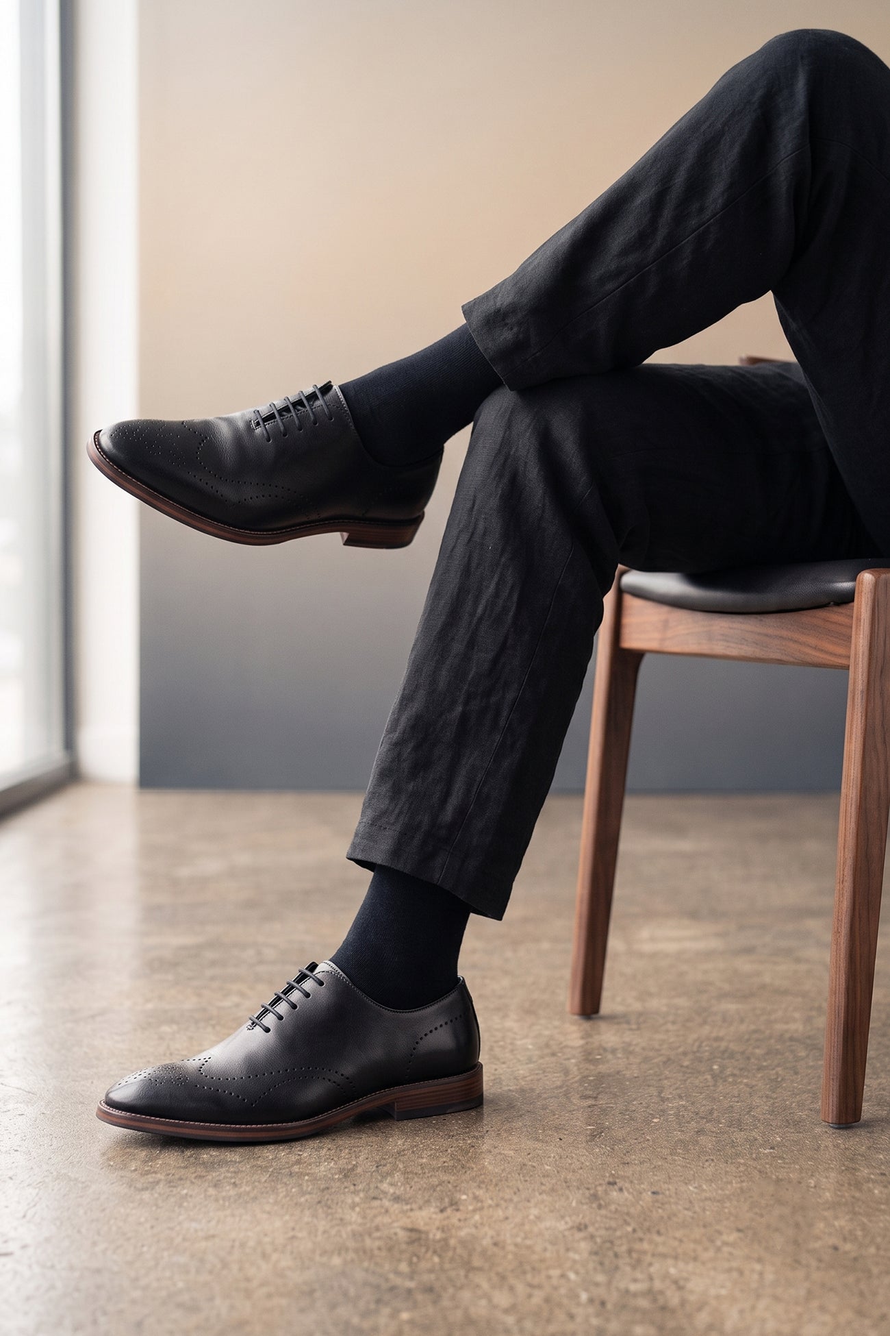 Man wearing Oswin Hyde London premium black leather wingtip brogues with a toe medallion pattern, contrast welt stitching, and a cushioned teal interior.
