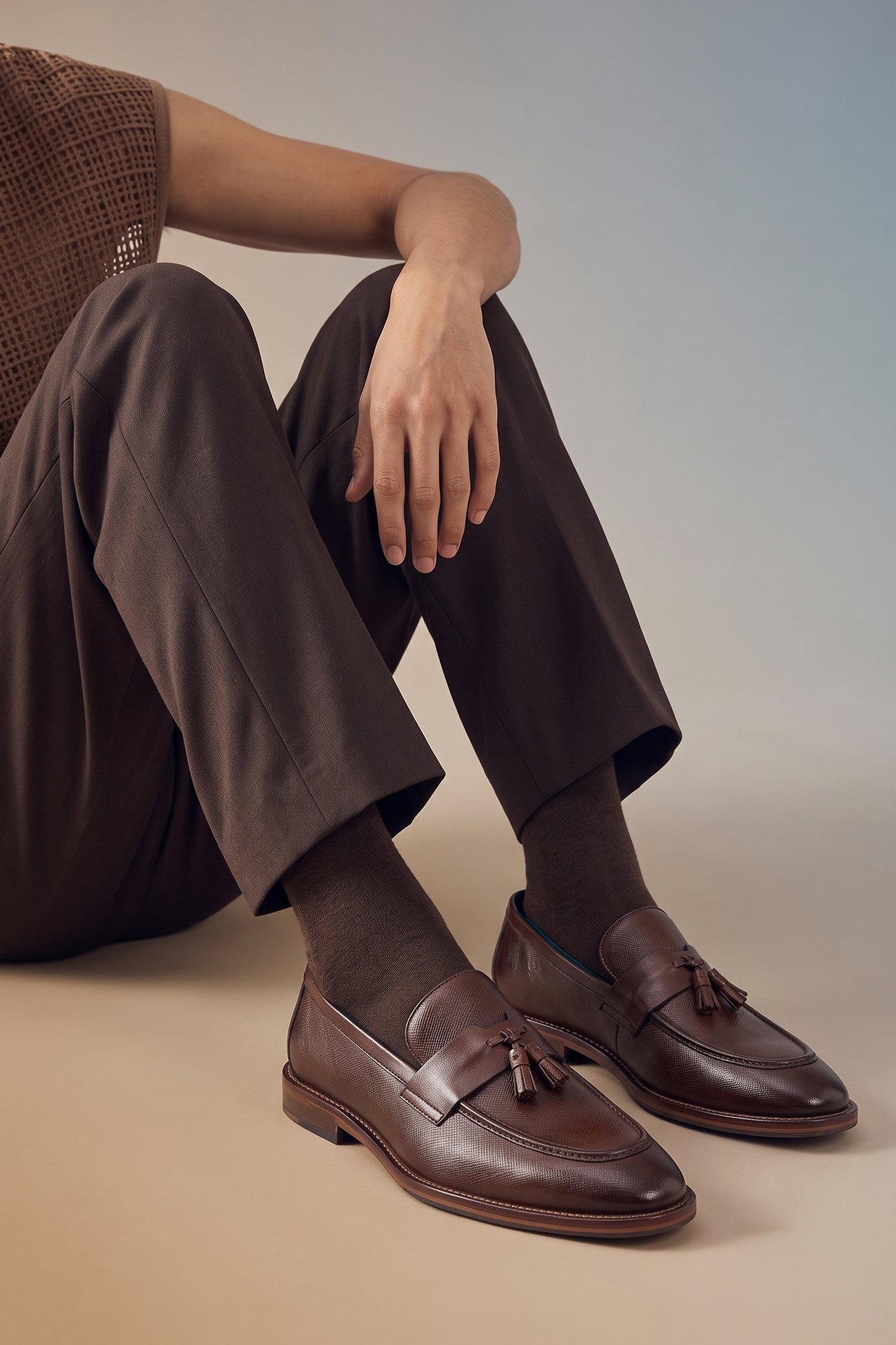 Man wearing Premium brown leather tassel loafers for men featuring a textured finish, burnished moc-toe details, decorative leather tassels, and a cushioned teal interior.