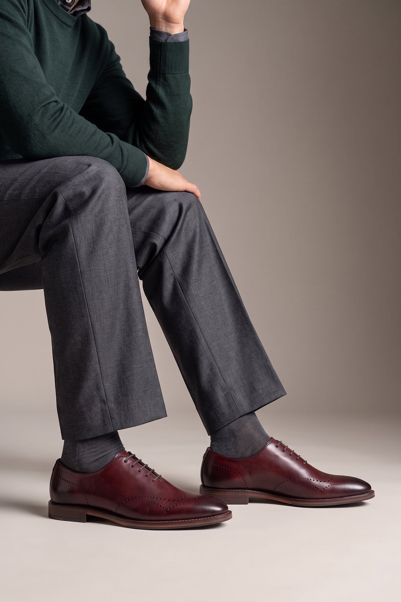 Man wearing Oswin Hyde London premium bordo leather wingtip brogues with a toe medallion pattern, contrast welt stitching, and a cushioned teal interior.