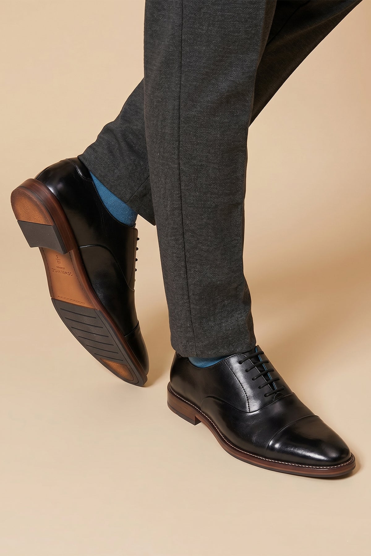 Model wearing Men’s Jarred Black dress shoes in high-quality black leather featuring a classic Oxford silhouette and toecap detail.