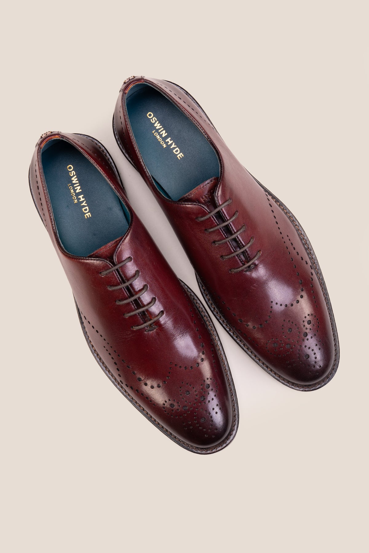 Oswin Hyde London premium bordo leather wingtip brogues with a toe medallion pattern, contrast welt stitching, and a cushioned teal interior.