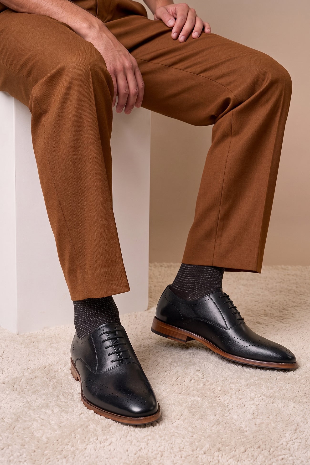 Man wearing Oswin Hyde London premium black leather wingtip brogues with a toe medallion pattern, contrast welt stitching, and a cushioned teal interior.