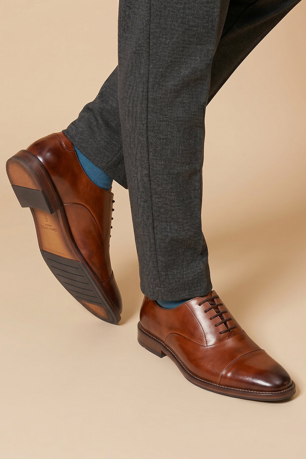 Model wearing Men’s Jarred Tan dress shoes in high-quality tan leather featuring a classic Oxford silhouette and toecap detail.