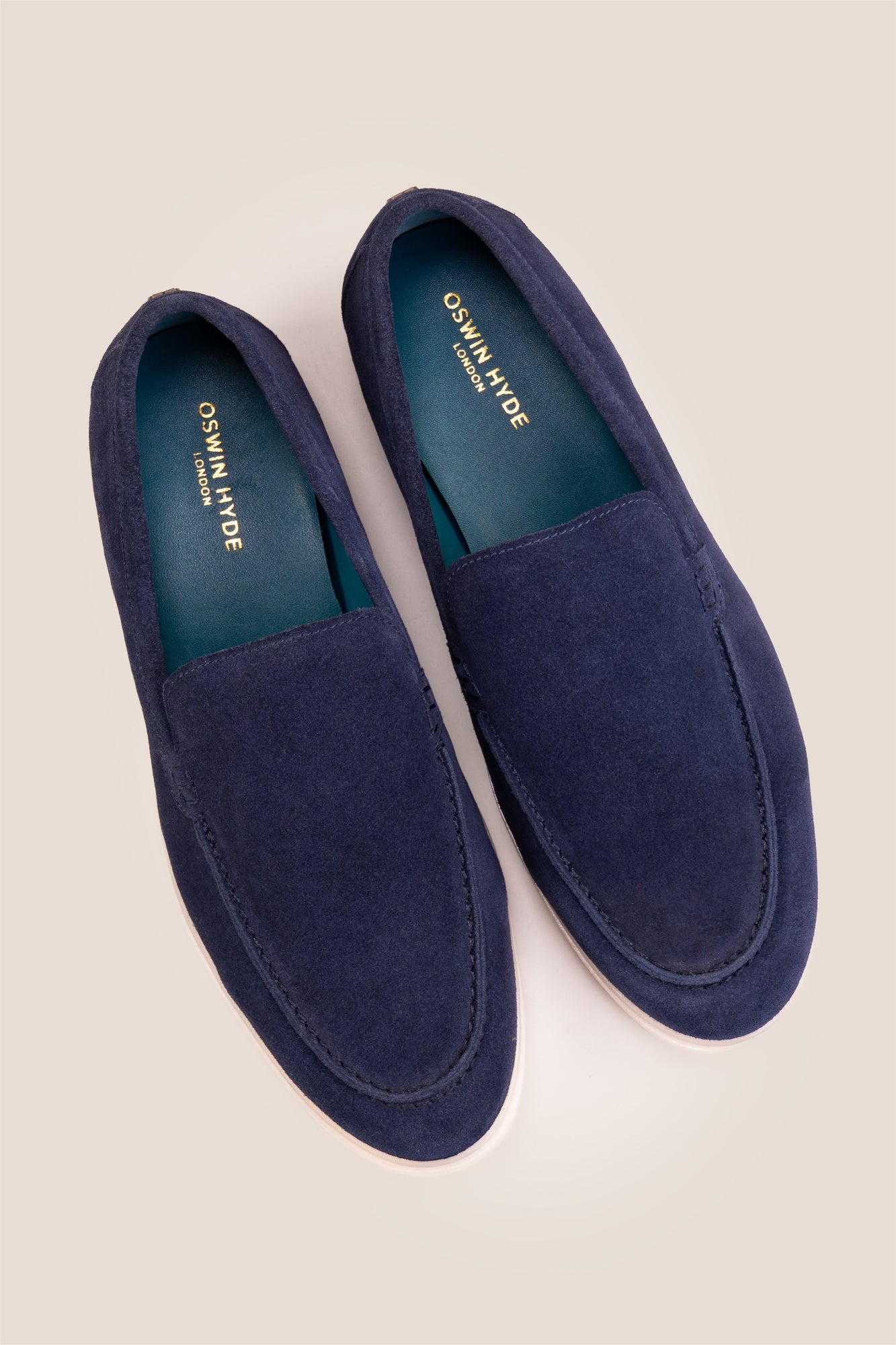Top-down view of Oswin Hyde Morgan Navy suede loafers, highlighting the teal blue inner lining and gold logo branding.