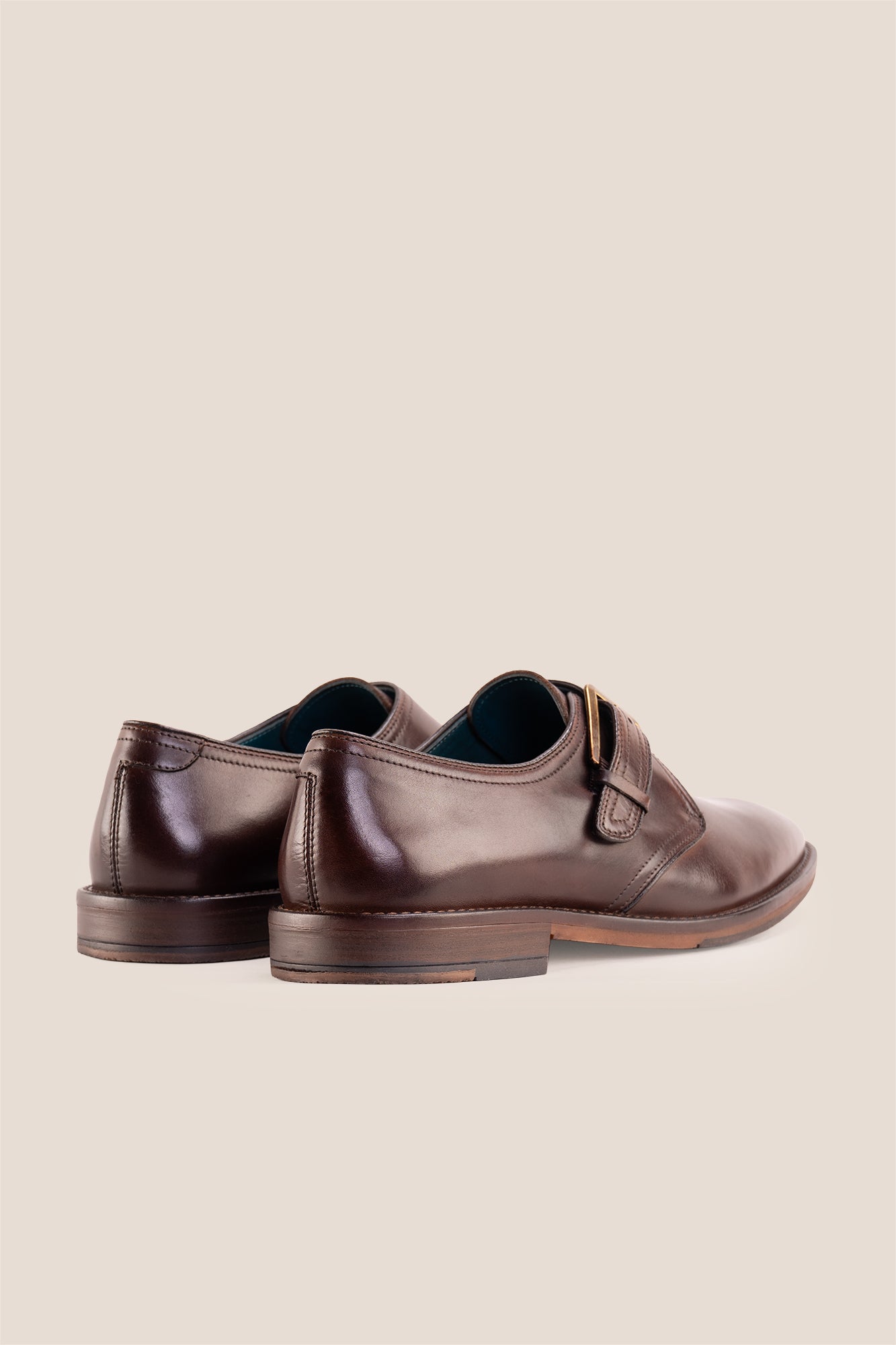 Premium men's brown leather single monk strap dress shoes by Oswin Hyde London featuring a plain toe, adjustable golden buckle, contrast sole stitching, and a cushioned teal interior.