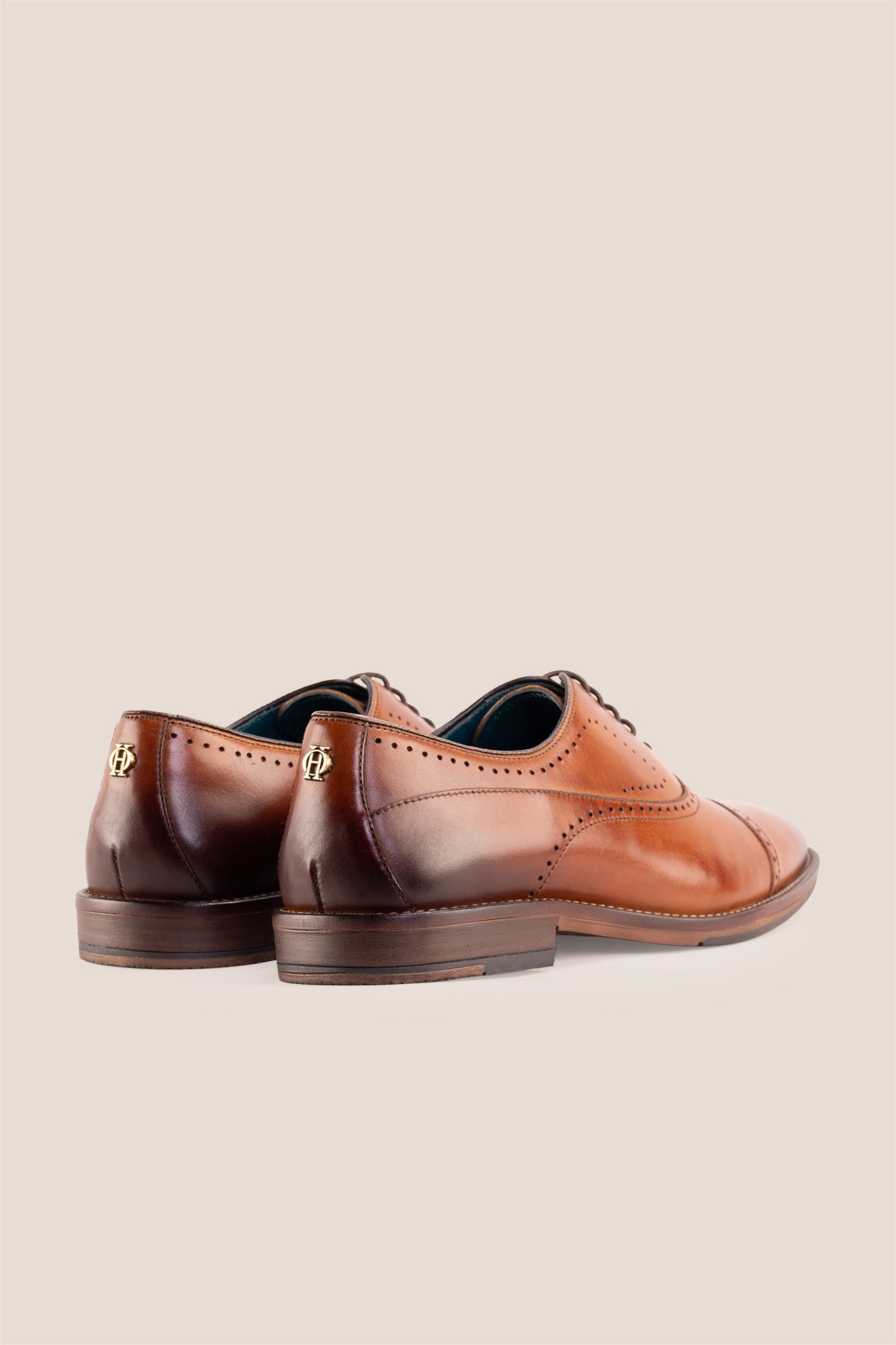 Premium men's tan leather oxford shoes by Oswin Hyde London, featuring a cap toe with decorative perforations, closed lacing, contrast welt stitching, and a cushioned teal interior.