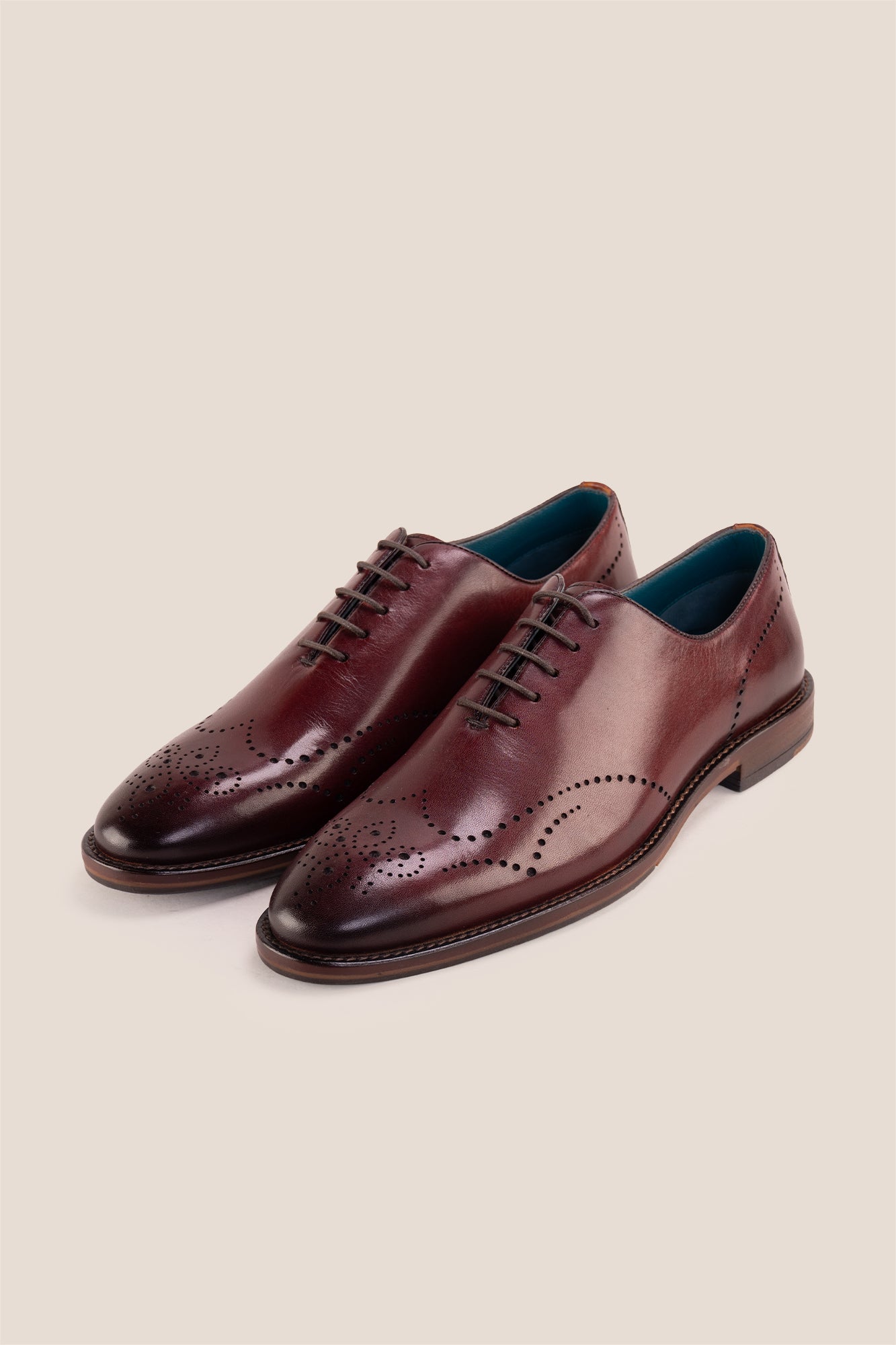 Oswin Hyde London premium bordo leather wingtip brogues with a toe medallion pattern, contrast welt stitching, and a cushioned teal interior.