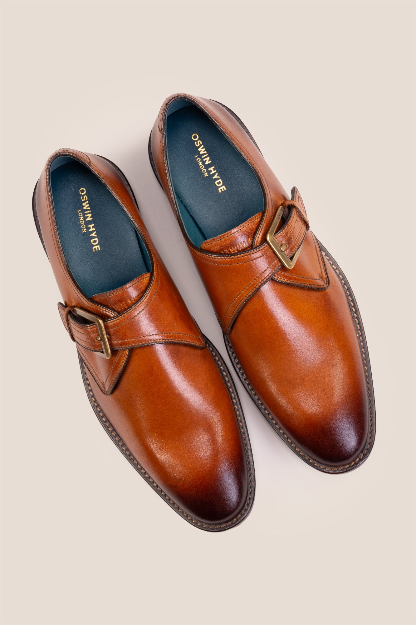 Premium men's tan leather single monk strap dress shoes by Oswin Hyde London featuring a plain toe, adjustable golden buckle, contrast sole stitching, and a cushioned teal interior.