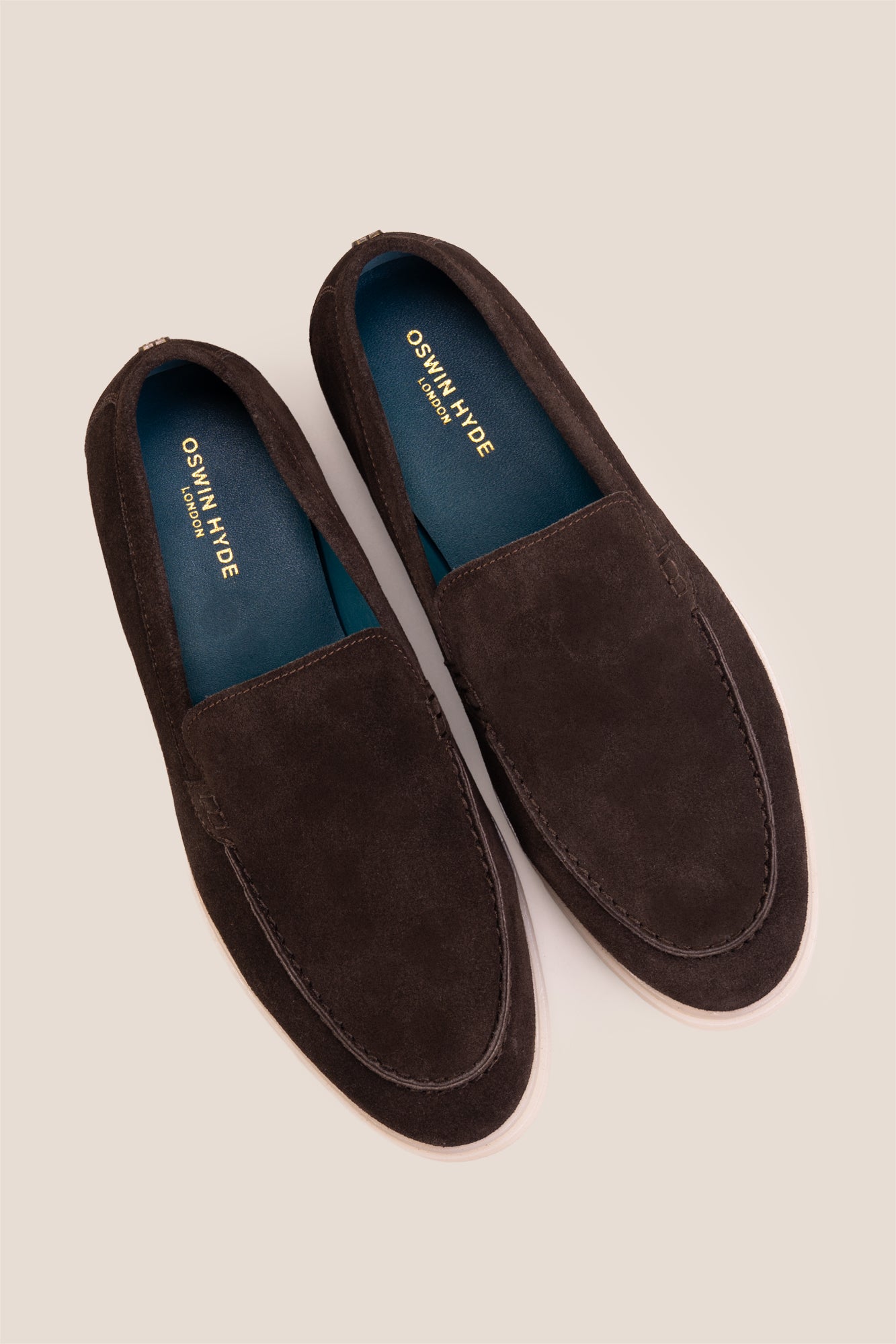 Top-down view of Oswin Hyde Morgan dark brown suede loafers, highlighting the teal blue inner lining and gold logo branding.