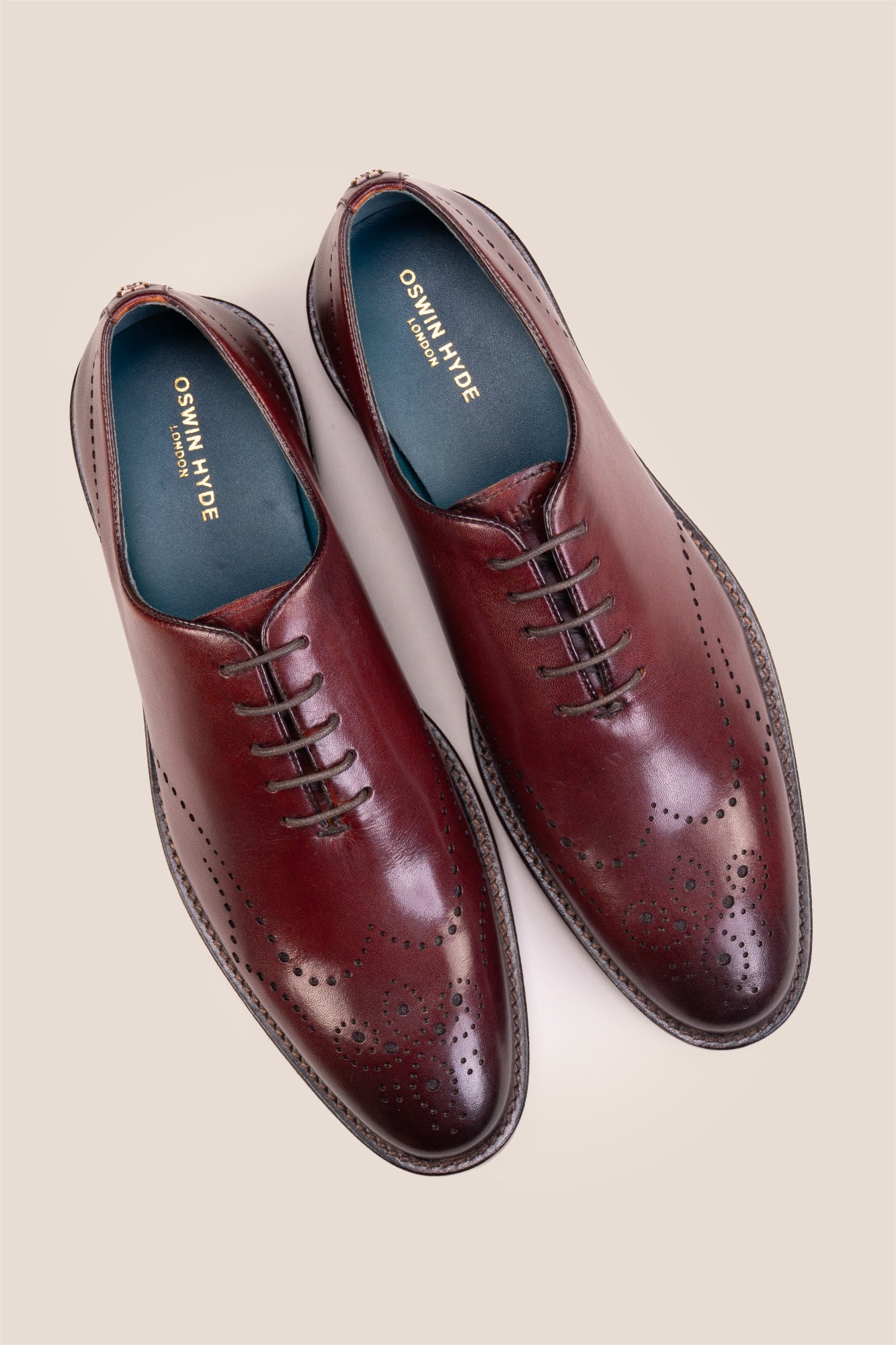 Oswin Hyde London premium bordo leather wingtip brogues with a toe medallion pattern, contrast welt stitching, and a cushioned teal interior.