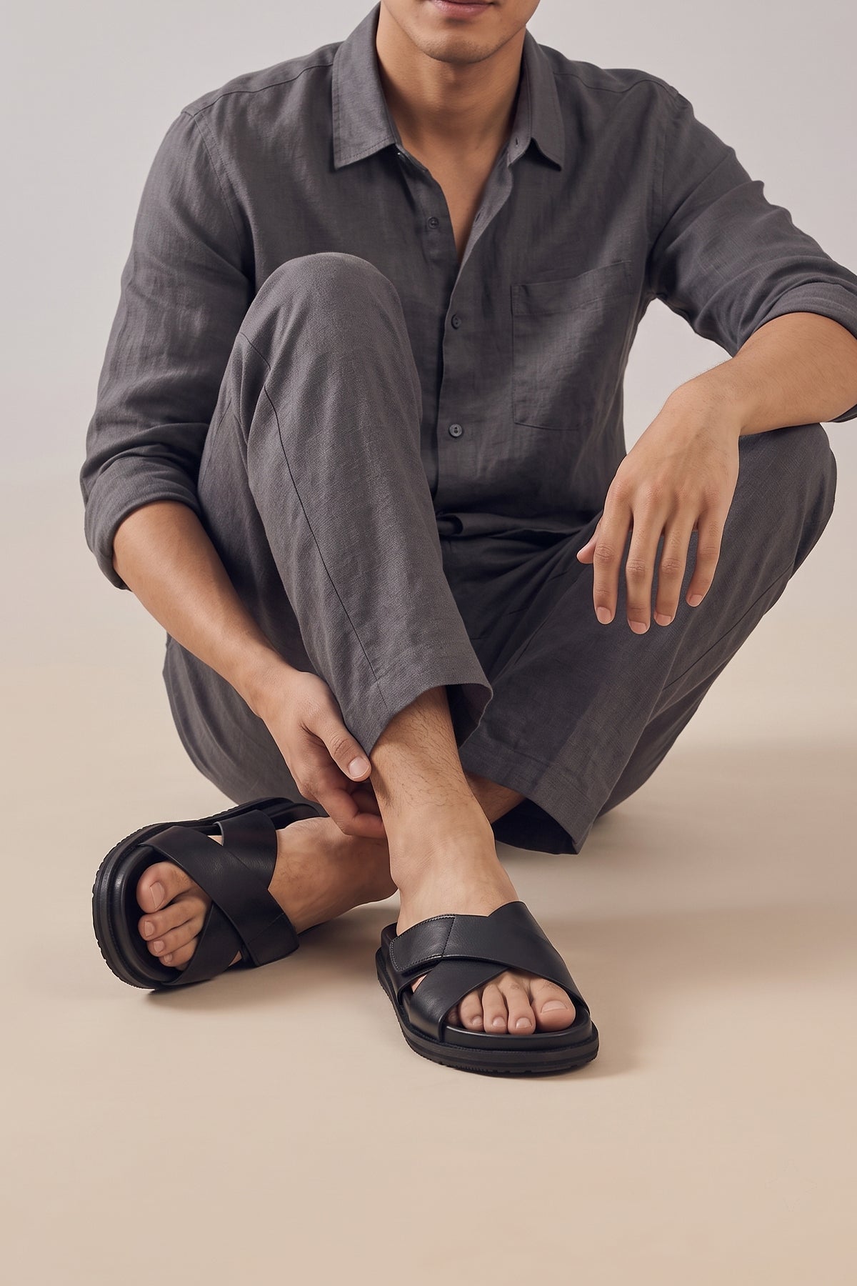 Model wearing Dylan Black leather men's sandals with cross strap and Velcro closure, ideal for casual wear, beach days, or summer adventures.