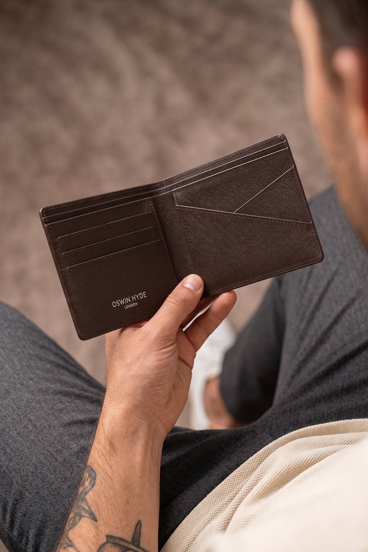 Man holding Marylebone brown saffiano leather bi-fold wallet for men by Oswin Hyde – slim luxury wallet with multiple card slots and durable textured leather finish.