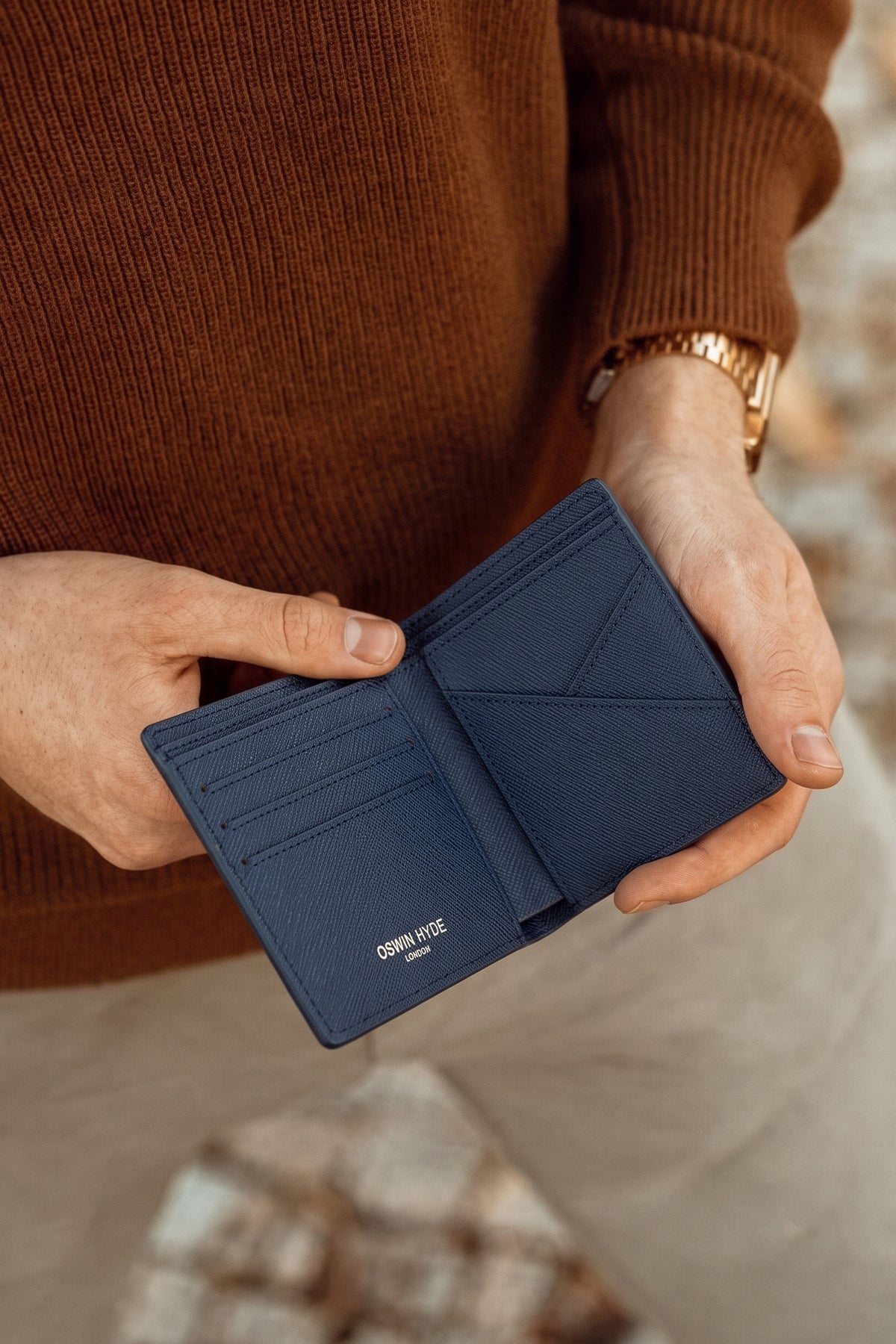 Man holding Marylebone navy saffiano leather bi-fold wallet for men by Oswin Hyde – slim luxury wallet with multiple card slots and durable textured leather finish.