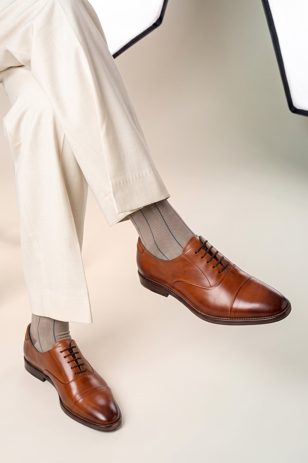 Model wearing Men’s Jarred Tan dress shoes in high-quality tan leather featuring a classic Oxford silhouette and toecap detail.