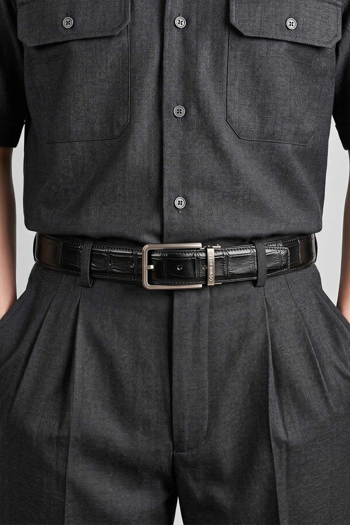 Man wearing Reggie Black crocodile-embossed leather men’s belt with a classic pin buckle, offering a sleek and sophisticated finish to any outfit.