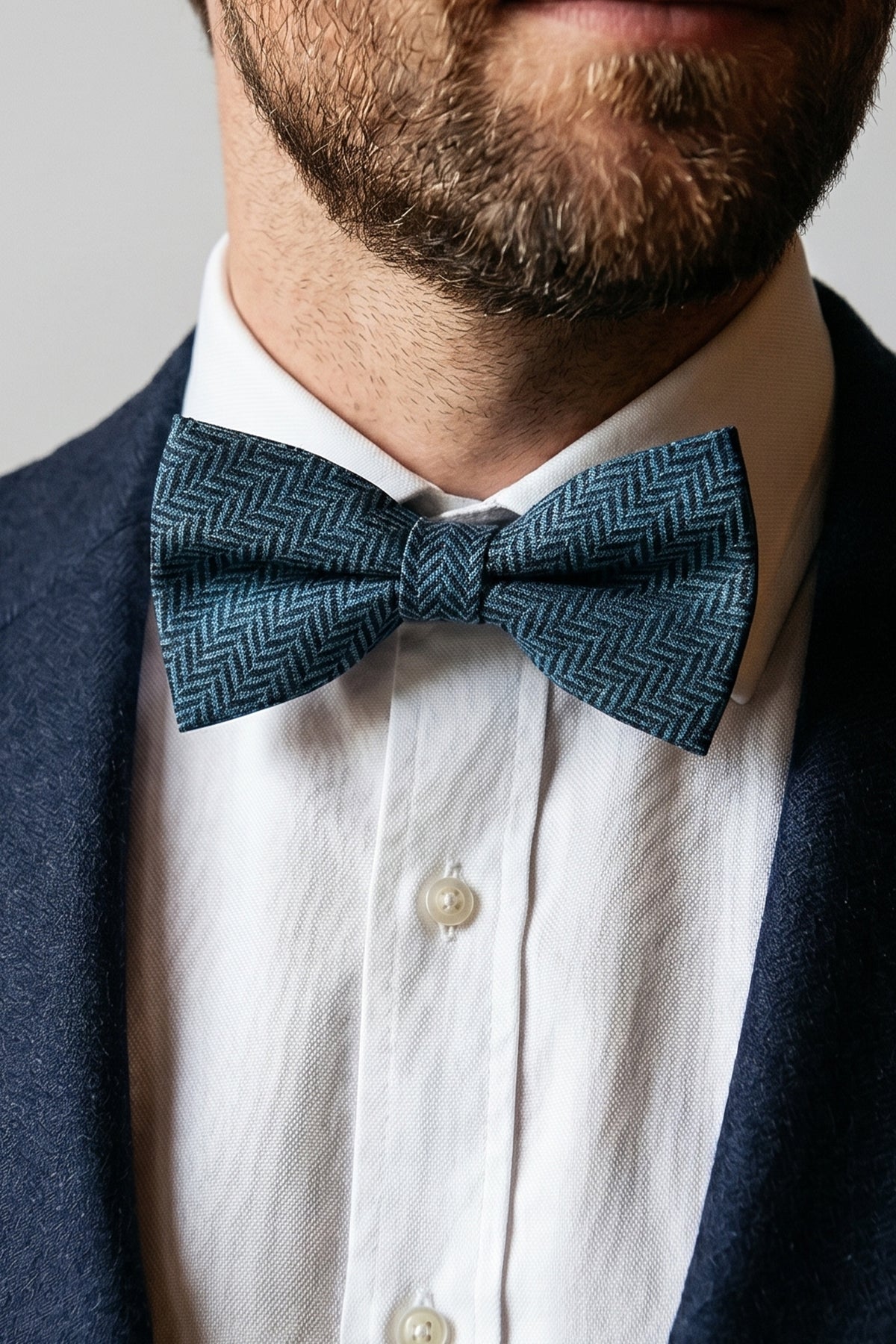 Man wearing Oswin Hyde Herringbone Blue Bowtie, featuring a classic herringbone pattern. deep blue hue and textured fabric