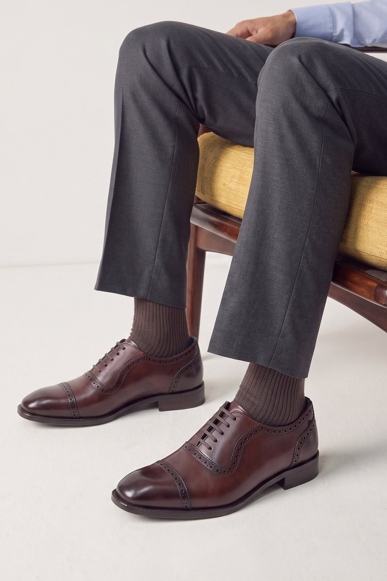 The men's smart brown oxford shoes showcase a refined cap-toe design with delicate brogue detailing and rich full-grain leather, perfect for weddings, formal events, and boardroom attire.