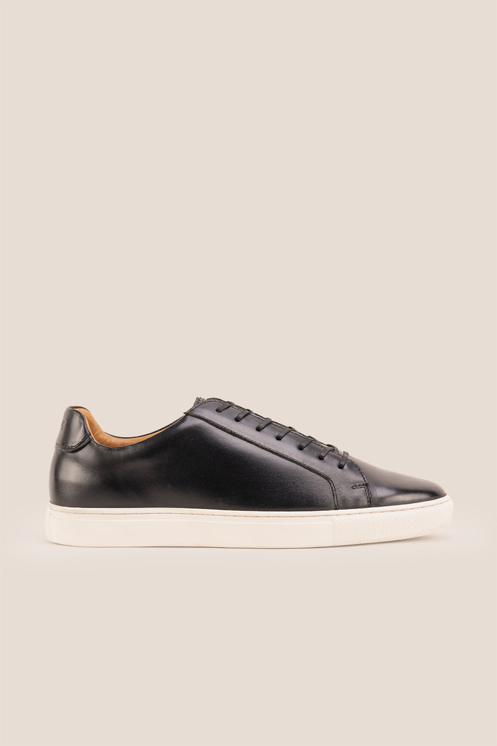 Black leather sneaker on a beige background