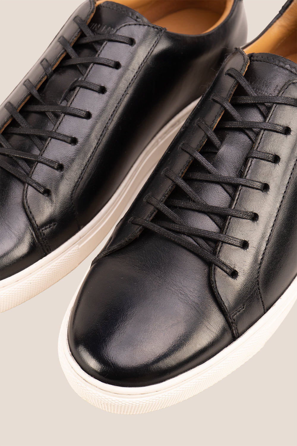 Black leather sneaker on a beige background