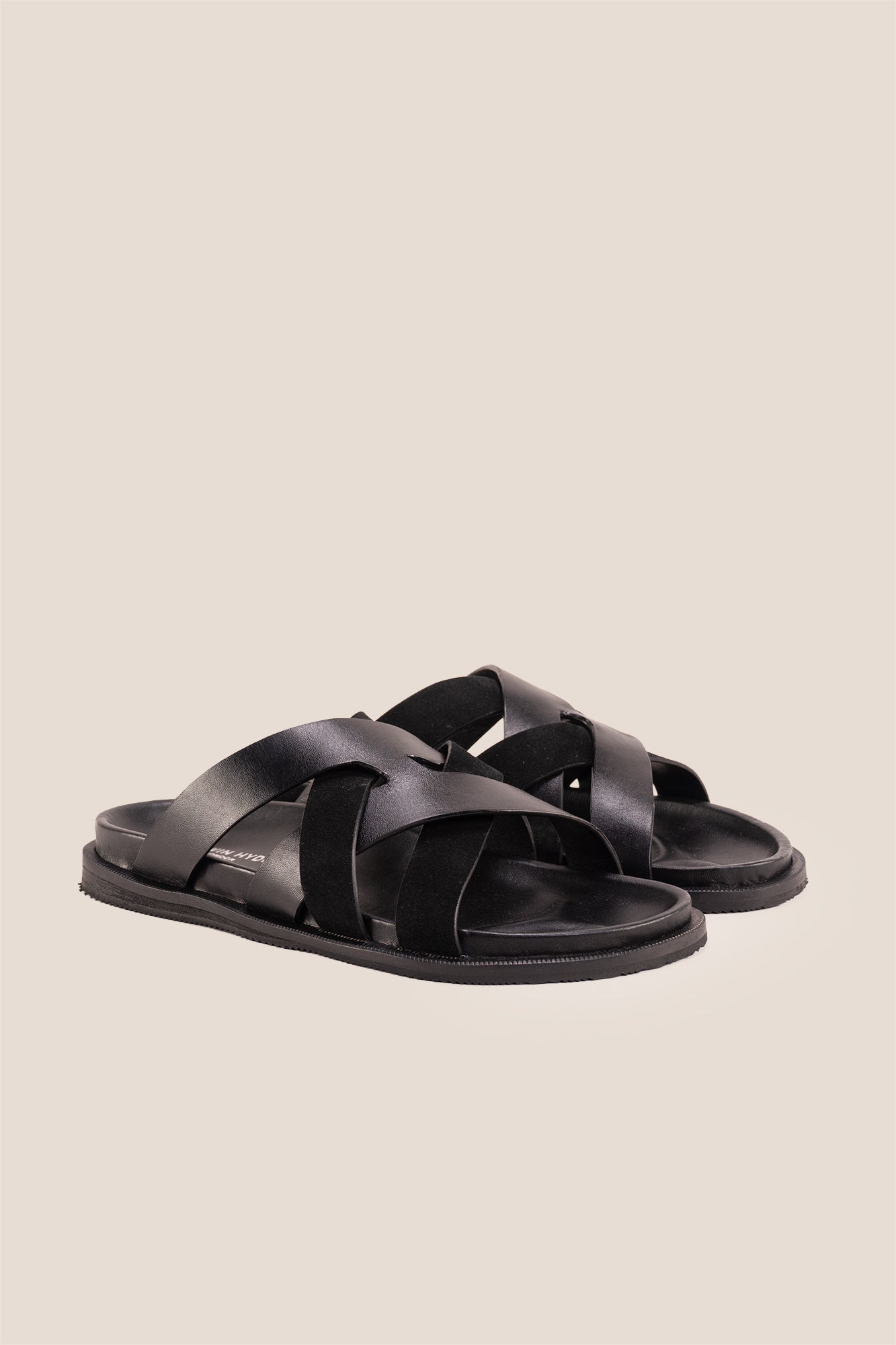 Men’s Rowan Black slide sandals featuring a minimalist black leather X-strap design and a sleek matte finish.