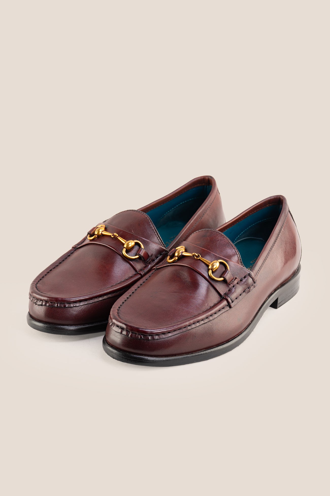Pair of Oswin Hyde Samuel Bordo burgundy leather horsebit loafers with gold buckle detail and teal lining.