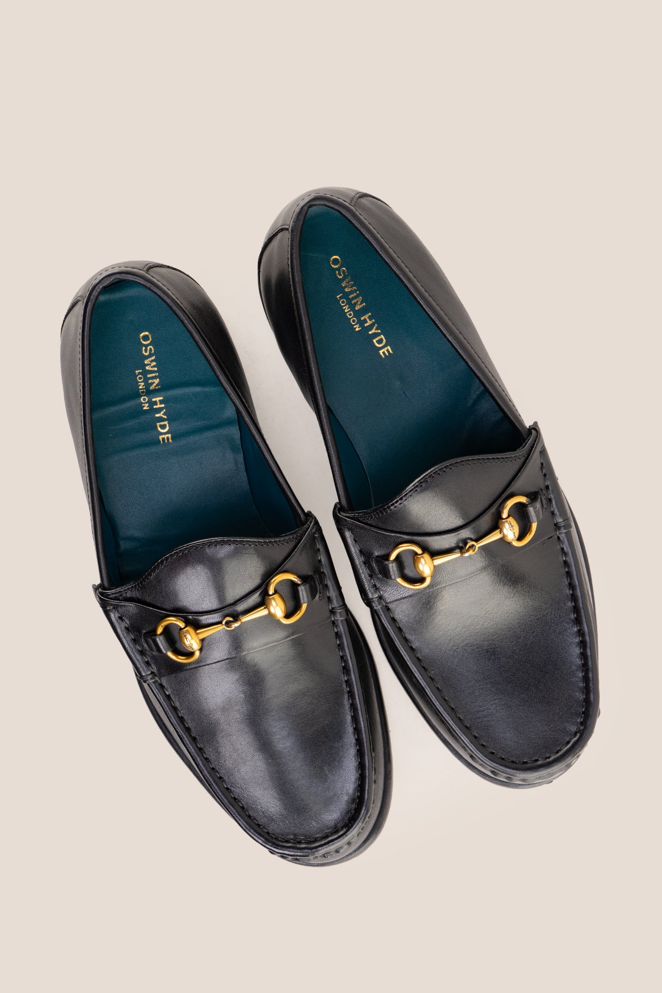 Pair of Oswin Hyde Samuel black leather horsebit loafers with gold buckle detail and teal lining.