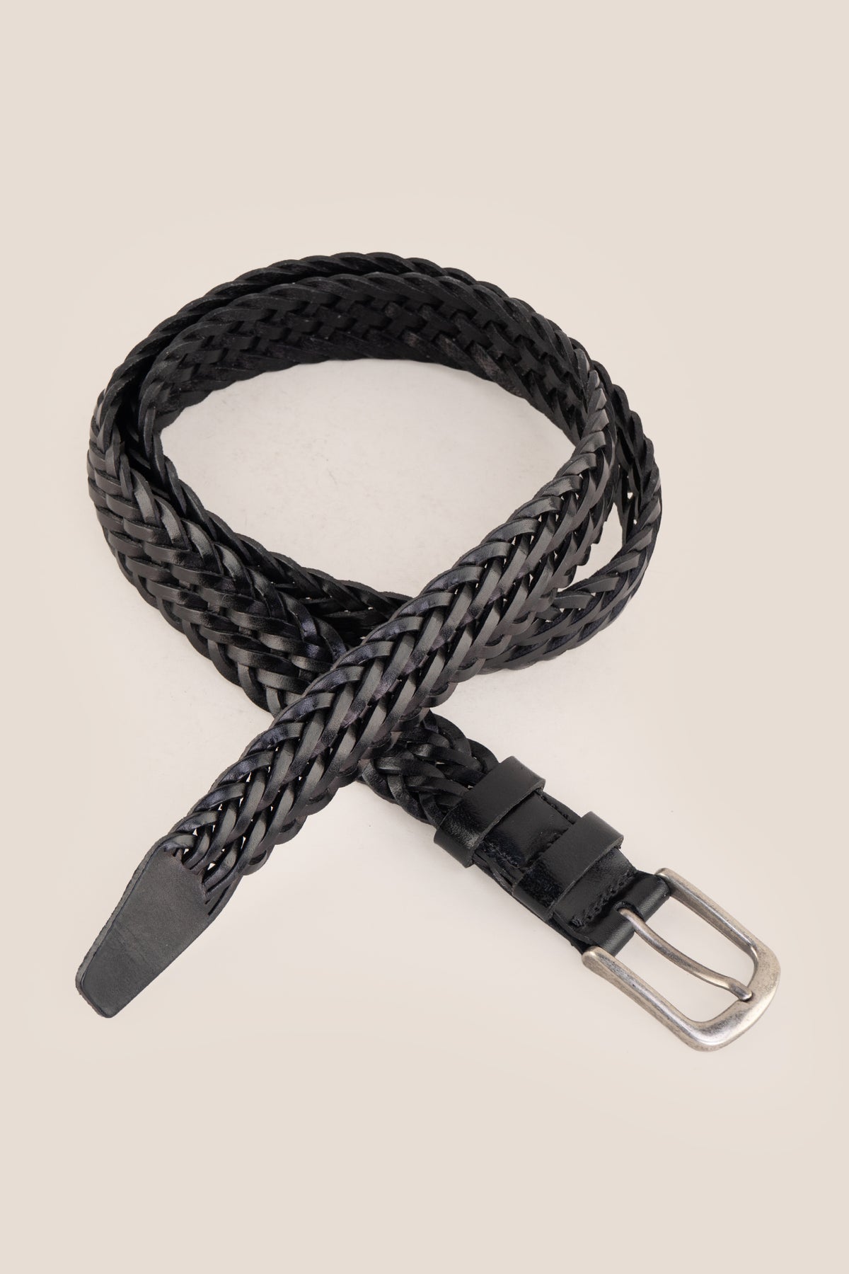 Milo black braided leather belt coiled with brushed silver buckle on neutral background