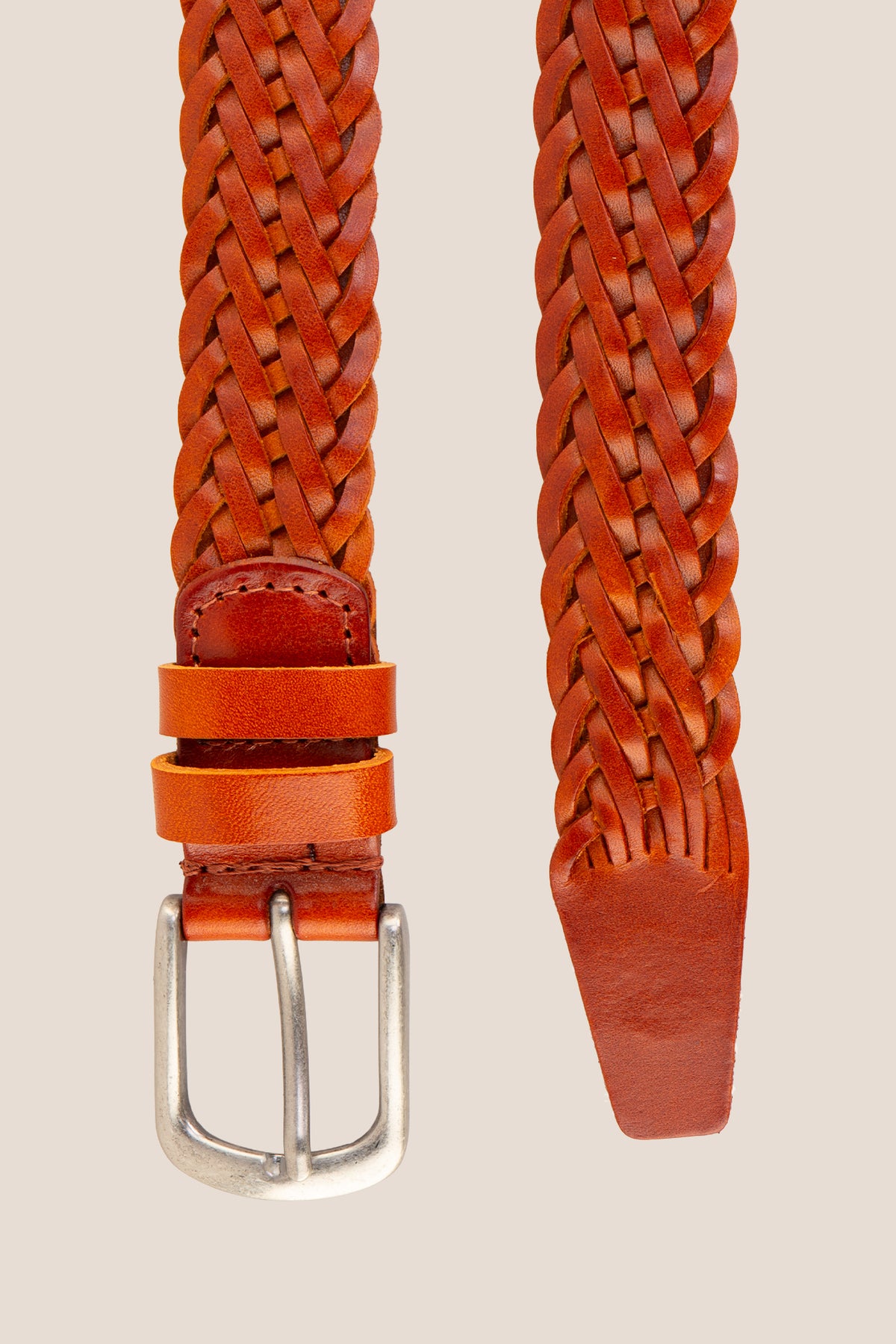 Close-up detail of the Milo tan braided leather belt strap tip and silver single-prong buckle.