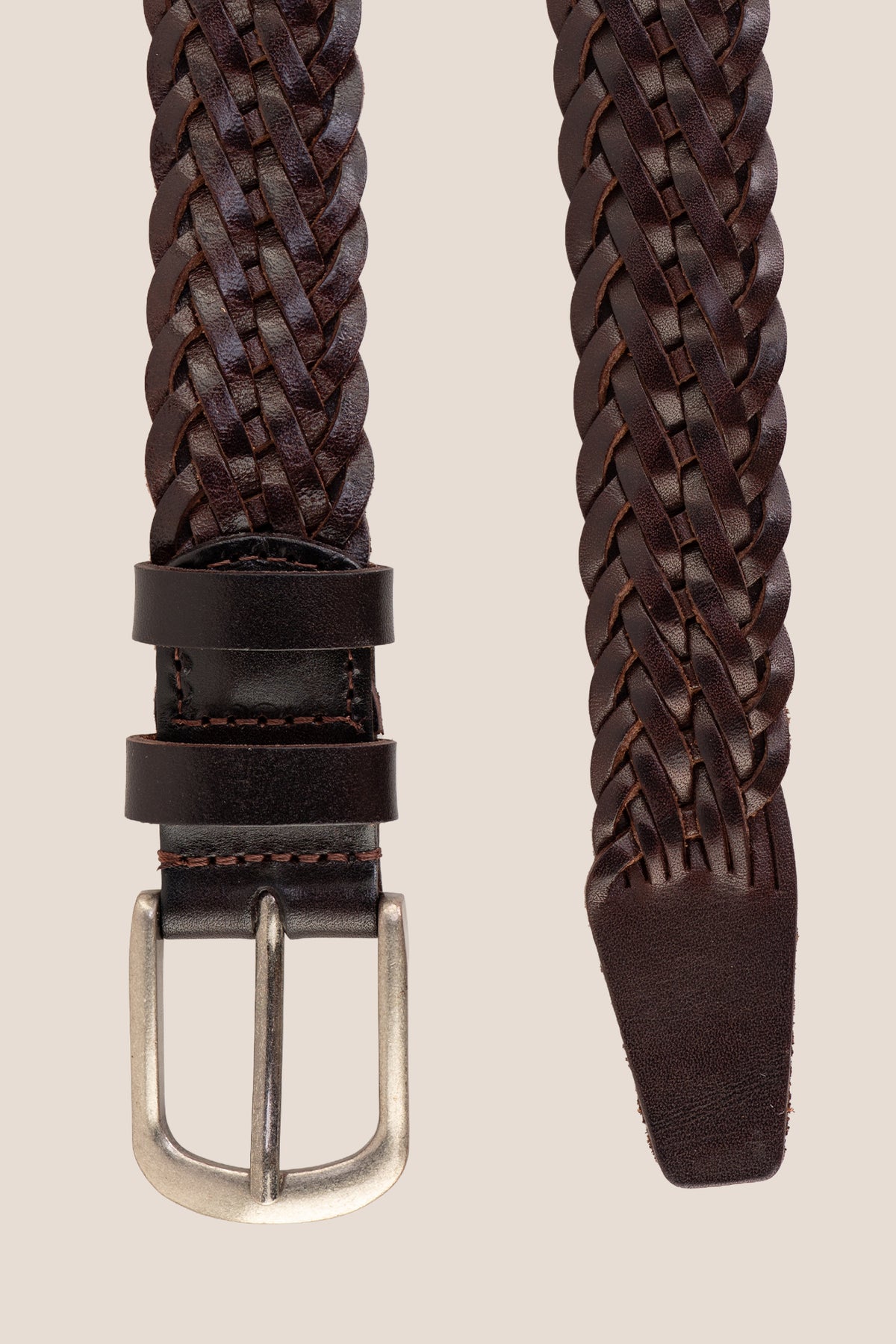 Close-up detail of Milo brown woven leather strap ends and brushed metal single-prong buckle.