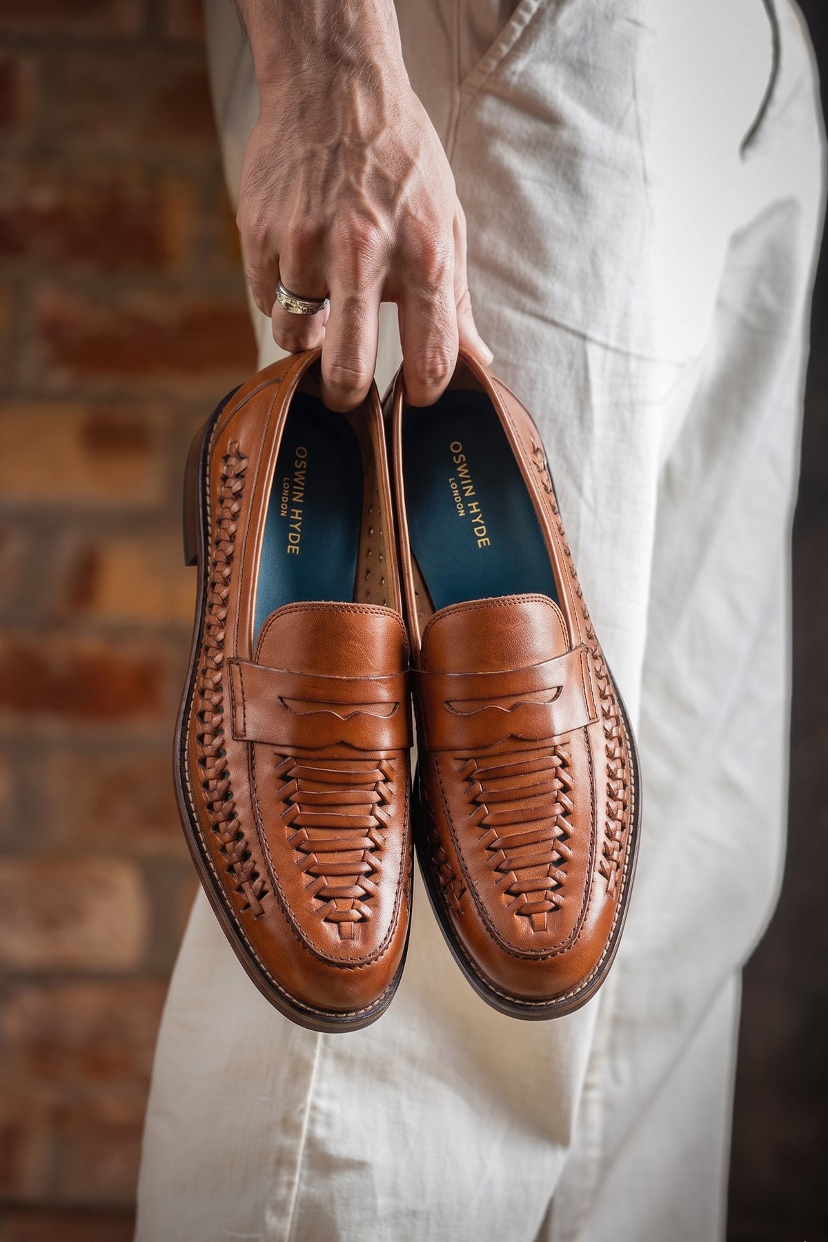 Model holding Finley tan woven leather loafer for men, showcasing premium craftsmanship with a sophisticated and timeless design