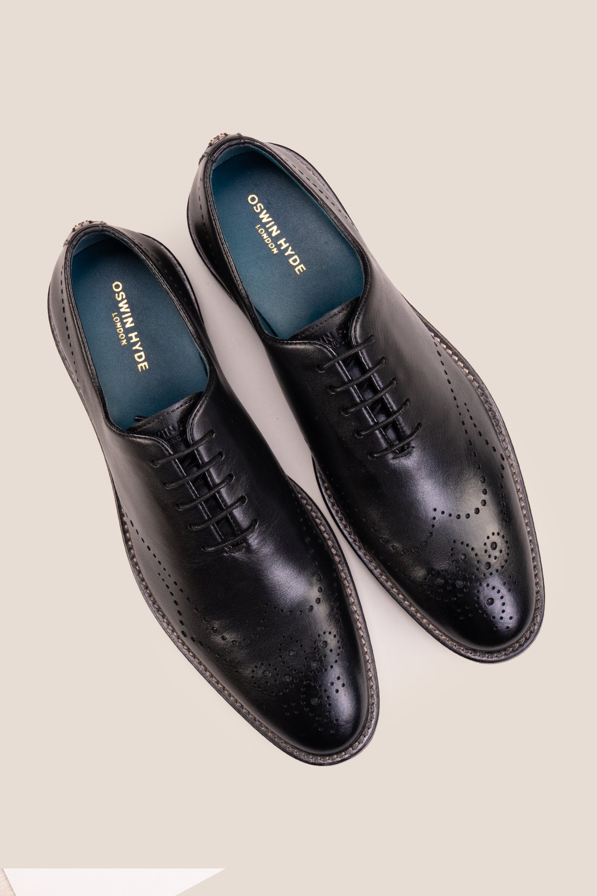 Oswin Hyde London premium black leather wingtip brogues with a toe medallion pattern, contrast welt stitching, and a cushioned teal interior.