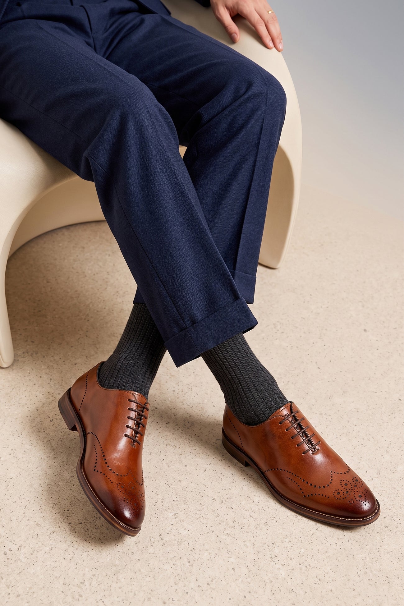 Man wearing Oswin Hyde London premium Tan leather wingtip brogues with a toe medallion pattern, contrast welt stitching, and a cushioned teal interior.