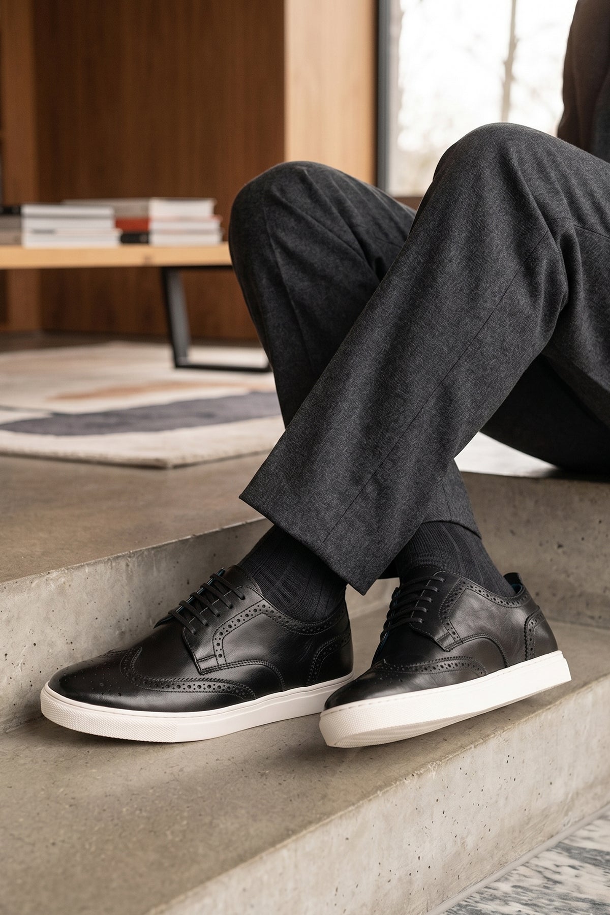 Model wearing Stan Black wingtip brogue trainer shoes for men, crafted from premium leather with classic wingtip detailing and modern trainer sole.
