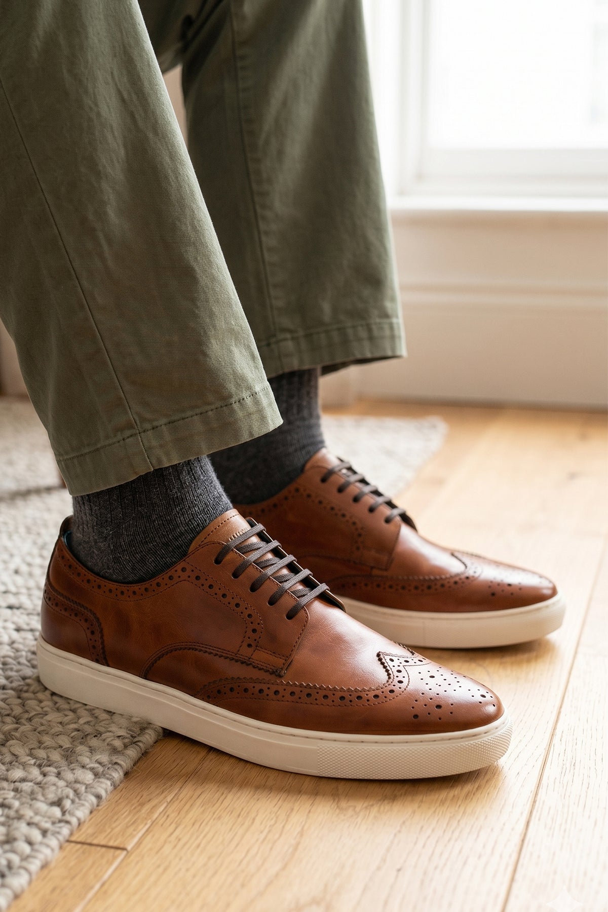 Model wearing Men’s Stan cognac leather wingtip brogues featuring traditional perforated detailing, breathable lining and a durable leather sole.