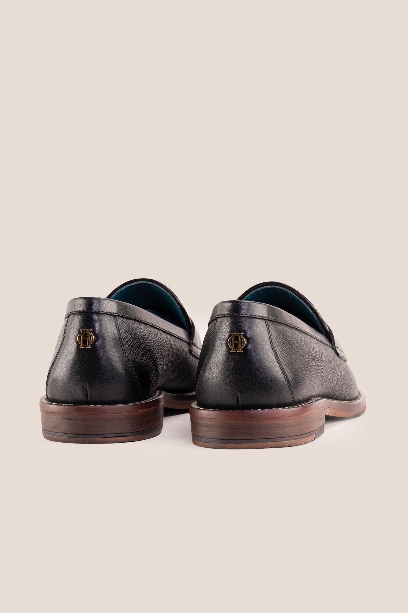Premium black leather tassel loafers for men featuring a textured finish, burnished moc-toe details, decorative leather tassels, and a cushioned teal interior.