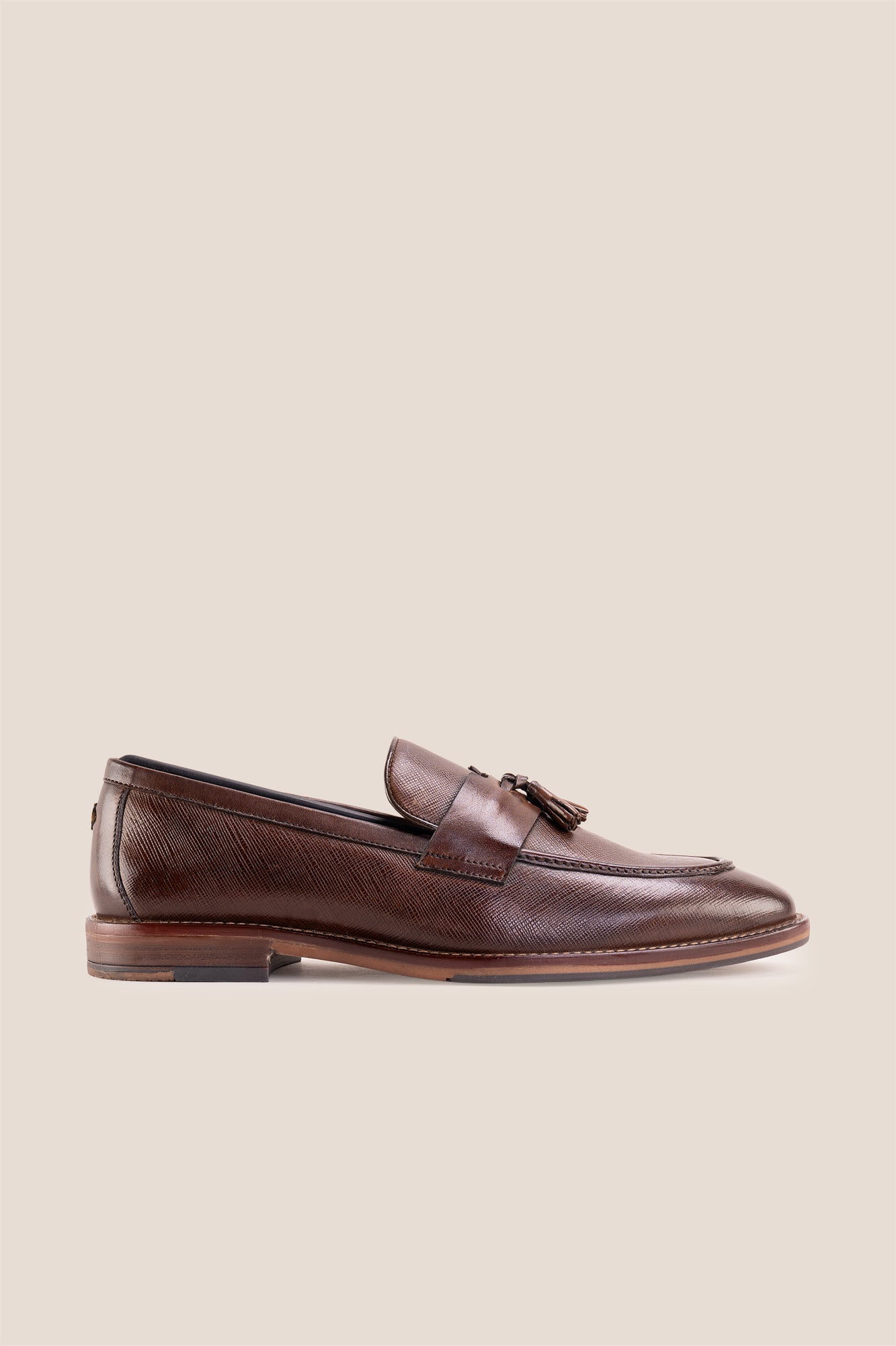 Premium brown leather tassel loafers for men featuring a textured finish, burnished moc-toe details, decorative leather tassels, and a cushioned teal interior.