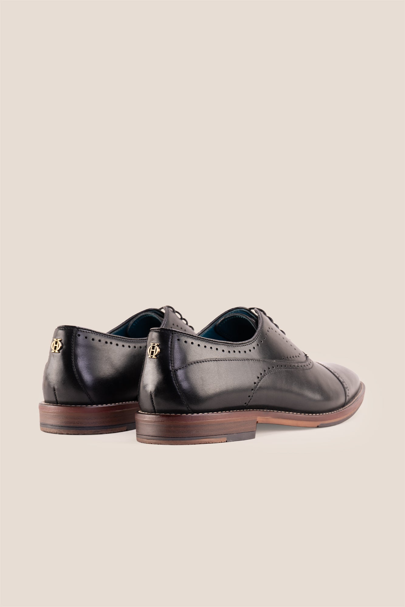 Premium men's black leather oxford shoes by Oswin Hyde London, featuring a cap toe with decorative perforations, closed lacing, contrast welt stitching, and a cushioned teal interior.